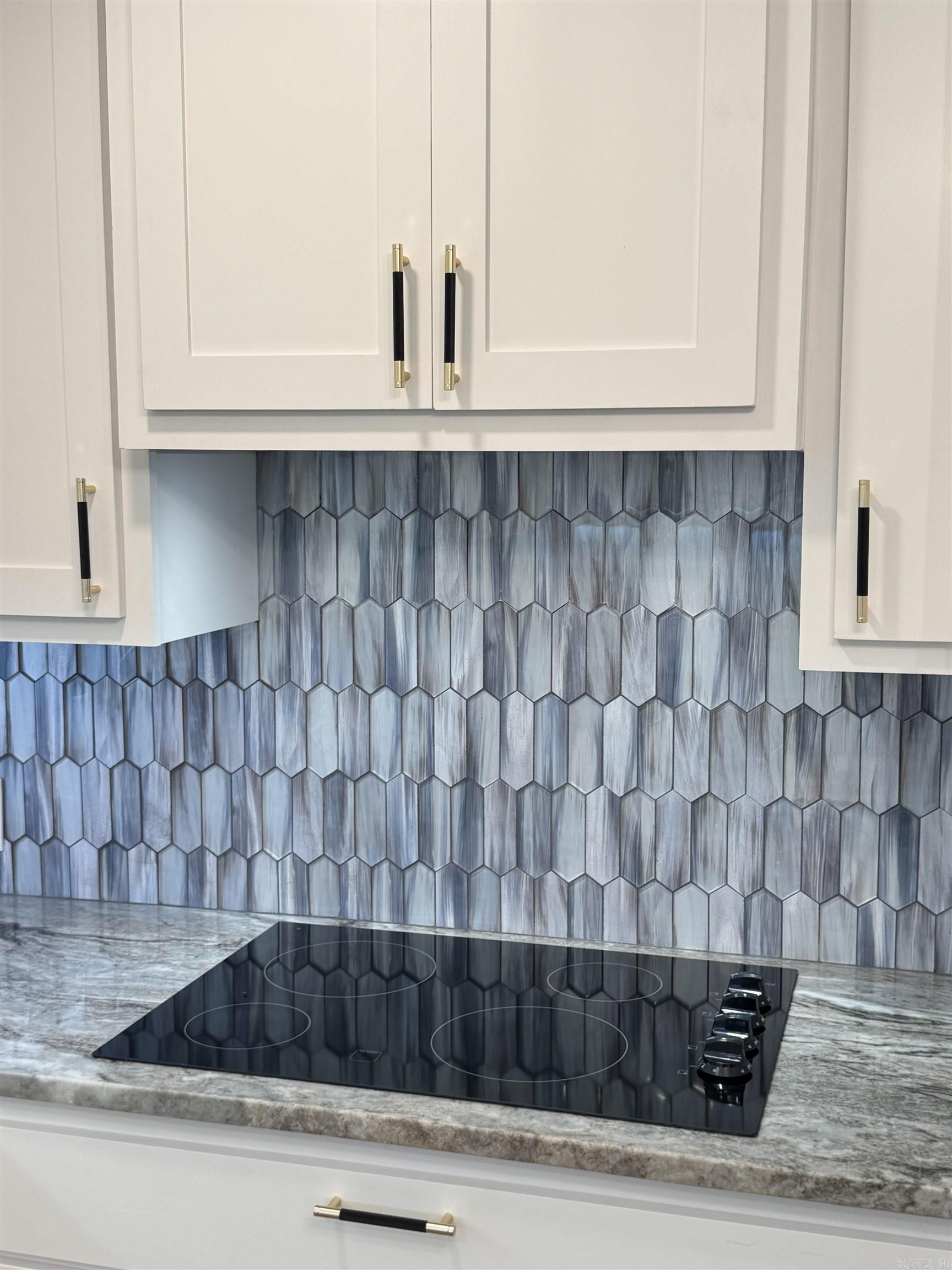 Glass backsplash, granite counters, cooktop.