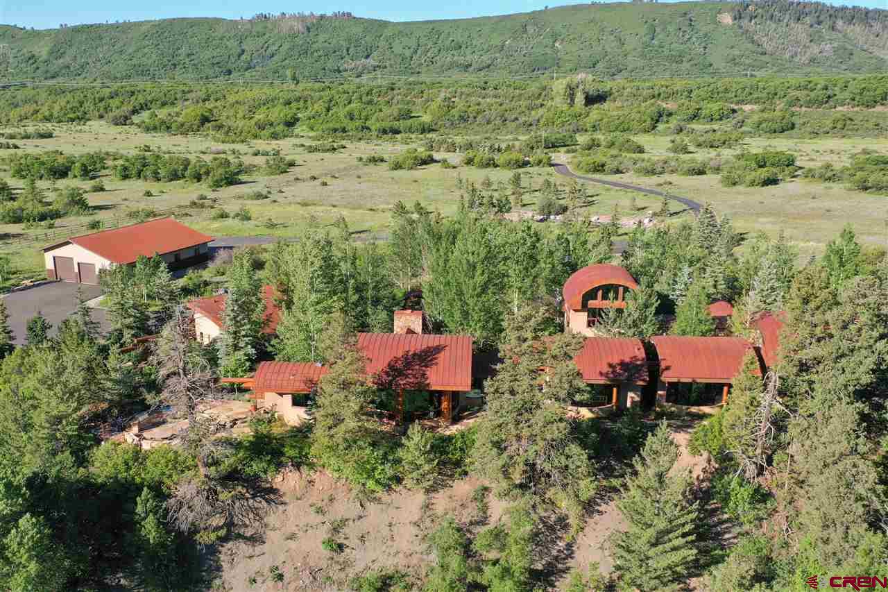 La Plata Canyon Ranch, located at the base of the majestic La Plata mountains on the La Plata River, is a stunning 15-minute drive west of historic downtown Durango. The property consists of 262 acres (4- separately deeded parcels), with roughly 3000 ft of the La Plata River. There are several improvements on this property including the main residence built in 2003 and designed by acclaimed architect, Jon Pomeroy.  The home consists of 7062 SF, 4 bedroom, 5 bath, & a 3-car garage. There is a 3312 SF equipment barn/shop and 4-stall horse barn.  The ranch has multiple ponds, an impressive stretch of river corridor, and extensive landscaping coupled with the scenic forest and lush river grounds.  The improved fishery (ponds & river) provides for great experiences & excellent hunting can be found on the ranch as well as direct access to hundreds of thousands of acres of San Juan National Forest.  Overlooking the La Plata river & dramatic vistas of the surrounding peaks & gentle vistas, the design combines cedar logs, glass, rock, steel, & sandstone.  Upon arrival at the strategically placed gated entry, the views will immediately grab your attention.  The paved drive leads you to the home’s courtyard with awe-inspiring landscaping featuring granite boulders (reclaimed from the La Plata County fairgrounds), berms planted with native grasses, trees, & shrubbery.  The attention to detail is paramount before ever stepping foot into the residence.  Unlike, many mountain ranches, La Plata Canyon Ranch enjoys complete paved access & is easily accessibility to countless recreation opportunities & city conveniences alike.  Skiing can be found within minutes from the ranch at the quaint Hesperus Ski Area & fine dining at the Kennebec Café.  The varying terrain allows for a plethora of wildlife including roving elk herds, deer, hawks & bald eagles. The property is fenced and cross-fenced, suitable for horses, cattle, goats or other livestock. Elevation 8,400 feet.  Taxes are exceptional low due to ag-status.  THE HOUSE.  The residence is discretely set back off of County Road 124. Upon entering the stately & welcoming gated entrance, the residence is approached through the paved drive that meanders through the natural terrain of the high mountains and lined with introduced foliage. Inside, the interior was designed to perfectly complement its setting. A stately steel & glass front door set the stage for this unique masterpiece. Off of the entry, the home media room featuring built-in shelving and fireplace. The north wing of the home is accessed by a gallery leading to the primary suite & two guest suites. The gallery is enhanced with two atriums.  Guest suite #3 is located on the second floor & is reminiscent of a tree house. All bedrooms are en suite & have separate thermostats to keep guests comfortable.  The primary suite is on the far north side of the house complete with water feature, ample closet/dressing room, large soaking tub, steam shower, & double vanity.  The laundry room is conveniently located on this side of the house. Flagstone floors are met with walls of glass & exposed log beams.  Solid cherry doors can be found throughout the home, 20’ ceilings & tinted glass throughout eliminating the need for window coverings.  The formal living room is circular showcasing the incredible surroundings.  The stonework juxtaposition the walls of glass & mammoth fireplace.  This is the centerpiece of the home with the dining & kitchen flanked to the south by a breezeway with access to the observation deck.  The kitchen is equipped with Sub Zero refrigerator, Viking six-burner range with griddle & double ovens. The outdoor living spaces features a sunken outdoor fire pit and kitchen equipped with double grills, two cooktops, and warming drawer.  This is a great place for family and friends to gather under the stars. Furnishings/equipment are available under separate negotiation.  Don't miss the 3D tour and drone video!