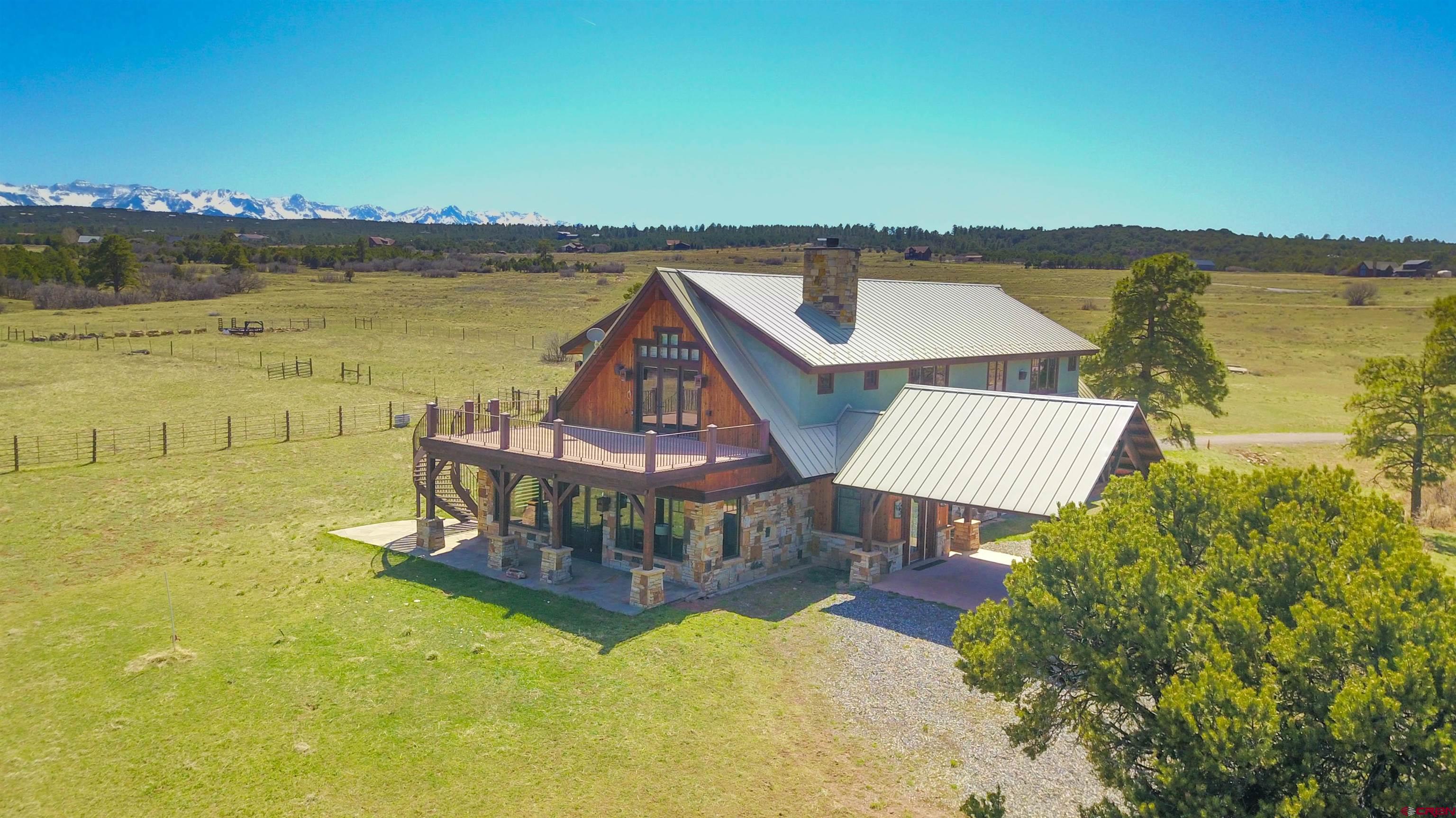 This custom home, offering vast 360 degree views of the Cimarron, Sneffels Ranges and valley floor. The house is set on the back corner of 40 acres, bordering a large private ranch as well as a greenbelt, giving owners and guests tasteful and private luxury. This property has 3,900 square feet of living space, a peaceful site for a retreat. Four elegant en-suite bedrooms are each equipped with soothing steam showers. Stay warm during Colorado winters with four grand fireplaces, one of which wood burning. Entertainment easily accomplished with the distinguished billiards room, equipped with an exclusive bar for cocktail connoisseurs. Sprawling decks allow owners the elevated advantage point of looking out at the San Juan mountains while staying in the comfort of their own homes. A kitchen with solid brass hardware that complements the home’s mountain style. Additional handicap tailored kitchen. A hydraulic elevator and a disabled bedroom and bath on level 1 make this home accessible for all. Plus a garage large enough to house four SUVs and all your toys. This custom-built home is sure to enthrall all. . As you enter through the Hand-Sculptured Glass Aspen Treed Door to the custom locally sourced hand-forged light fixtures this home has had every item considered and executed to a masterpiece. With its vast views of the San Juans, Cimarrons, Valley Floor, and massive decks when you see the Timber-Framed Porte-Cochere it will guarantee a Grand Entry. End of the road privacy here in Ridgway Colorado.