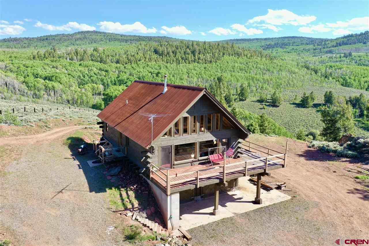 Beautiful custom handcrafted log home is positioned on 151.5 acres up Vulcan outside Gunnison, Colorado. This property is mostly surrounded by BLM land. Great mountain views of the West Elk Wilderness, Continental Divide and Uncompahgre mountain with lush meadows and Aspen groves where the elk and deer roam. Master bedroom includes a on suite bathroom and views of the pond on the southern end of the property. The natural spring feeds the cistern system for the house.  There are 2 generators to provide evening power for the house & to recharge the small battery system. The kitchen includes hand crafted cabinets, stone counter tops, a beautiful Vulcan gas cook stove and propane refrigerator. The interior is finished with wood floors, solid wood doors and hand crafted Engelman spruce vaulted ceiling beams. The house sits over a 6 car garage that is large enough to park a backhoe in and still have rooms for trucks and toys. Off-grid living at it's finest!