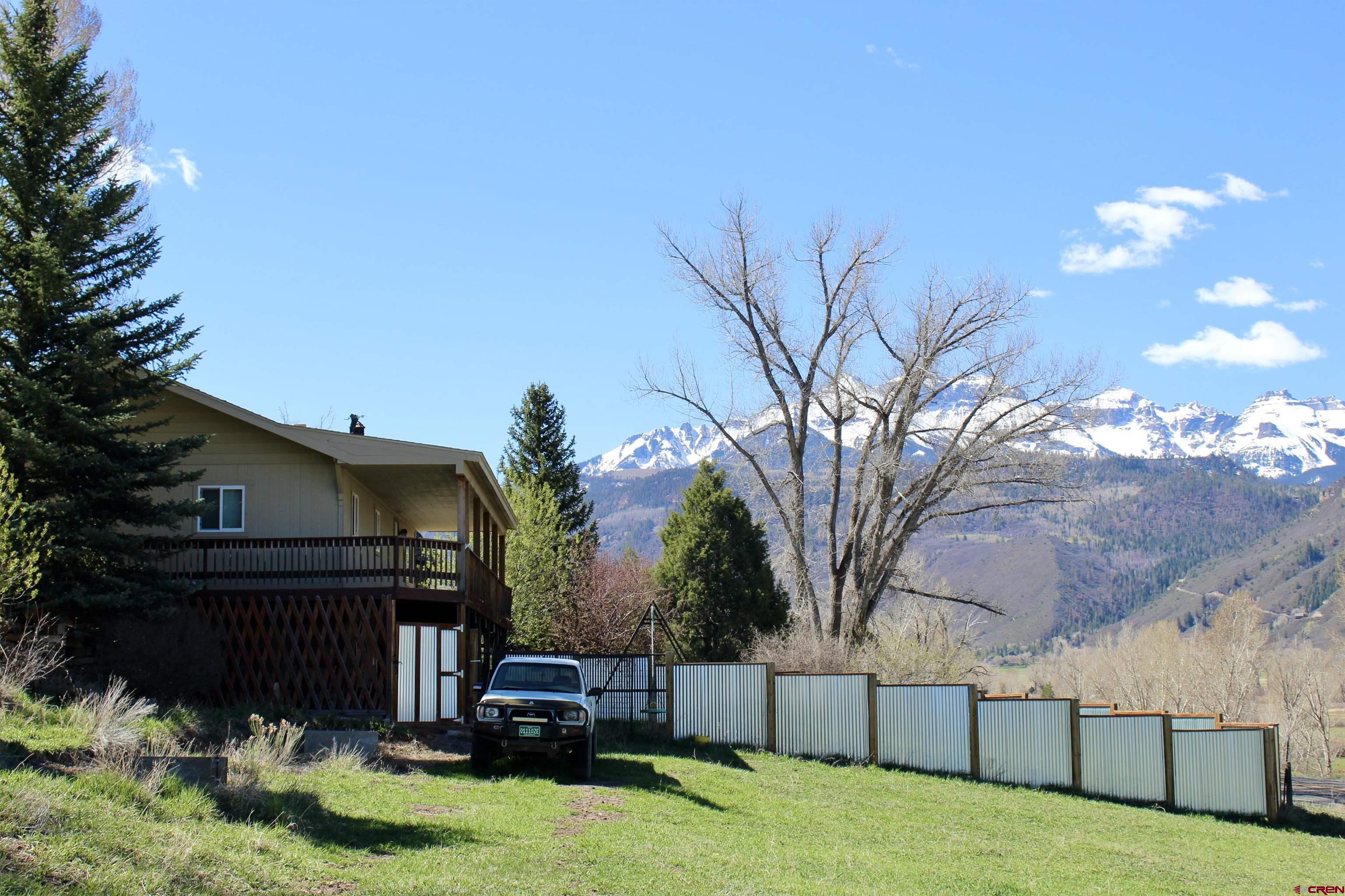 LOCATION! LOCATION! LOCATION! MOUNTAIN VIEWS AT THEIR BEST!  Here is your chance to get a one-of-a-kind property close to Ouray and Ridgway with everything you need.  Located just off 550 and across from Orvis Hot Springs, this 1.85 acres is complete with a 3 bedroom/2 bath home, partially completed basement which already has a heat source, detached 3 bay garages with a shop, and a gorgeous, enclosed gazebo with electricity overlooking the Sneffels range. The gazebo could be used as a reading room, observation area, hot tub room, art room or more. The basement can be a 4th bedroom, office, work out area, or anything you dream up. There is also a privacy fenced backyard for your 4-legged friends, children to play, or to enjoy yourself.  With the home sitting up above the highway, the deck has spectacular views of the mountains.  The property has 2 access points and has room for all your toys and a roomy shop for your projects.   Come see all the possibilities.  Empty and easy to show!