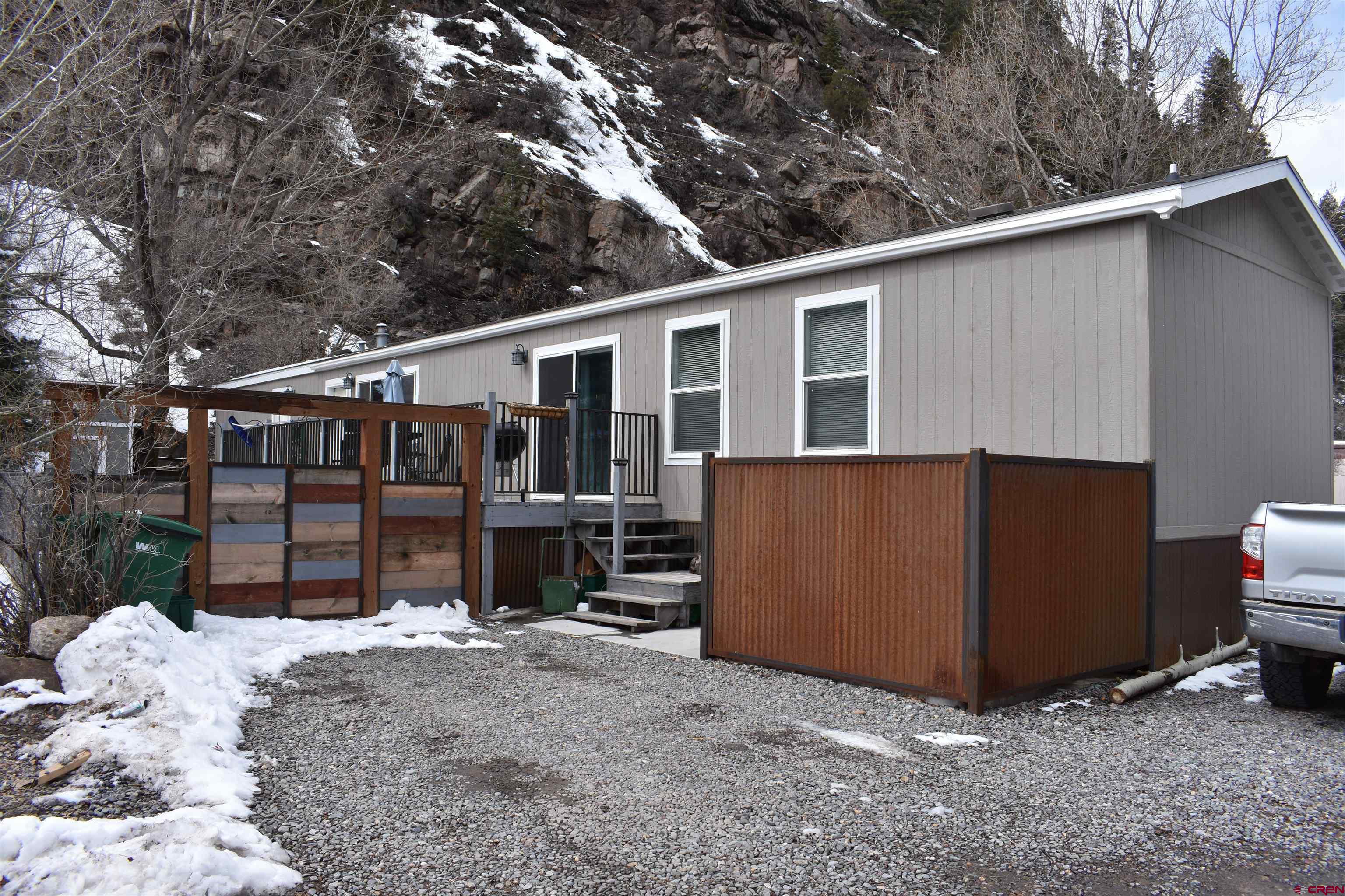 This beautiful, meticulously maintained three year old home is located in the 4J RV park in downtown Ouray, Colorado! Just steps away from the Ouray Hot Springs Pool and Park, shopping, restaurants, hiking trails and all Ouray has to offer!  This home has many desirable features. 85 pound snow load, sheetrock walls with 9 foot vaulted ceilings and beautiful crown molding throughout the house. The kitchen is large with plenty of storage in the bright white cabinets, lots of countertop space, an apron sink, stainless steel appliances, soft close drawers, stacked stone backsplash, and a pot filler faucet above the stove. The open concept makes the kitchen/living/dining area very inviting with lots of south facing windows making the area light and bright. The windows offer lovely views of the Amphitheater, Abrams, and Hayden mountains. The primary bedroom has an ensuite bathroom with double sinks, a tiled shower and a walk in closet. There are two additional bedrooms and a shared bathroom. The laundry room is located off the dining area. In the main living area there are two sets of sliding glass doors leading to a large south facing deck with all the mountain views and Colorado sunshine!  The fully fenced, landscaped yard features a very large mature cottonwood tree, grass, private hot tub and storage shed. The lot rent for this home is $437 per month and that includes your water, sewer and trash. Unit must be owner occupied. All buyers will need to be approved by the 4J park prior to closing. Don't miss out on this great opportunity to make Ouray your home!