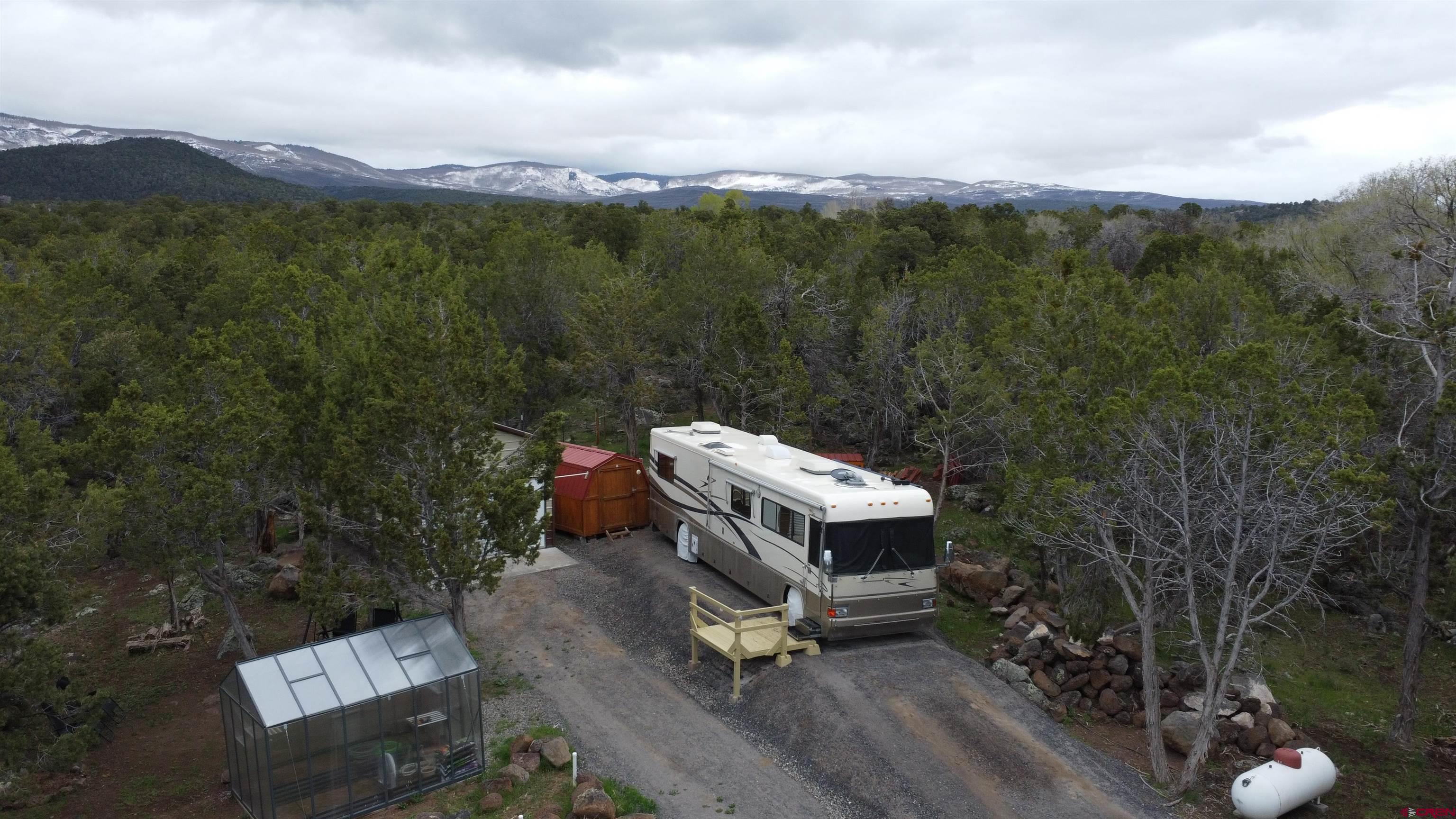 Own your own Grand Mesa Mountain retreat!  This 4.9 acre wooded property has it all.  A paid and installed Colby water tap, A engineered and installed septic system, a 200 amp electric service, and both views and privacy.  Behind the gate this property is set up for RV living currently.  It has a 20x14 insulated shop, a 20x8 shed that is set up with a laundry room, and if that is not enough it has a Greenhouse! Enjoy the paths that are established throughout the property or the garden area.  Peaceful living at its best.  The property is also being offered with the 40’ motorhome for a total price of $260,000.00.  If purchased with the motorhome the property also comes with the back-up generator.  You could use this while you build your dream home or just use it like it is.  The Town of Cedaredge has so much to offer with the 18 hole golf course, The Grand Mesa Art Center, Town Park and then you also have access to the Grand Mesa National Forrest.  Where you can enjoy hunting, fishing in one of the hundreds of lakes, hiking, cross country skiing, mountain biking, ATVing, or many of the other activities.  Welcome to your own little slice of Heaven!