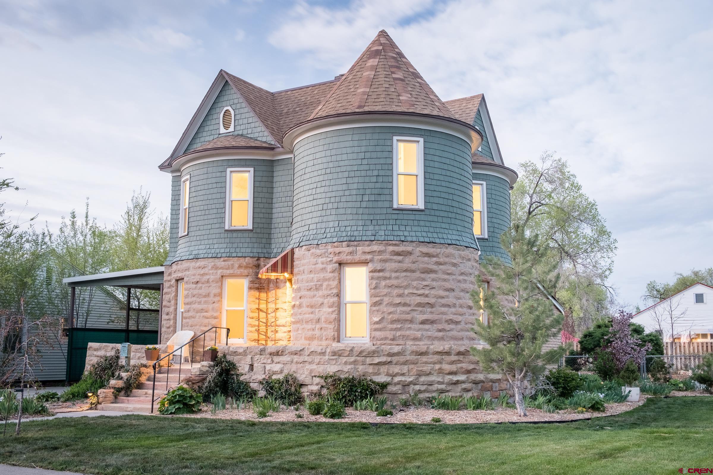 Own a rare piece of Colorado History located just minutes from downtown Montrose, restaurants, pubs, the river trail, fly fishing, the Uncompahgre River and live music venues.   Built in 1906 by Mr. Cassell, a local rancher and dairy farmer. the "Castle House", as it is known, is centrally located in the downtown Montrose area, within walking distance of brew pubs and restaurants. Situated in an up and coming quiet neighborhood. It is just two blocks from elementary schools and parks. The Montrose Regional Hospital is an easy seven blocks way. The French Chateauesque and Turn of the Century Farmhouse is built from locally cut sandstone. There is one complete turret and two partial turrets. The foundation is at least 7’ deep and was originally constructed to accommodate the storage of milk from the local dairy.  There are 3 bedrooms and 2 full bathrooms plus an additional small sunny room in the turret. It has a closet but is quite perfect for an office, nursery, library or artist studio. The bedroom downstairs could also be an office or family room. Large closets- two per room, in each bedroom. Two living spaces on the lower floor. There is generous storage space in both the attic and the cellar. The cellar is accessed via stairs from the kitchen and has a concrete floor.   The backyard is fenced with a spacious outdoor covered porch off the kitchen. This home sits on a corner of two downtown streets with mature trees on 4 city lots! There is ample space to build a future large garage or carriage house with access from the alley. This home is located within the City's "Redo" district and the construction of an ADU or Accessory Dwelling Unit is permitted and encouraged.   Mature shade trees, fully landscaped with fenced back yard and complete sprinkler system. Off-street parking. Carport. Tall enough for RV or boat storage. Comfortable house for entertaining, with separate bar area. This entire home and property have been renovated with the following NEW Upgrades and complete replacements/restorations: Original 1906 wood floors- refinished All remaining floors in kitchen and baths are replaced with hard surface flooring 100% Paint- inside and out. New Sump Pump and water heater New Bathroom Velux skylight All New upgraded 200 amp electrical service and breaker panel New Central Air Conditioning Full kitchen replacement- premium soft-close cabinetry, GE oven with Air Fryer, GE microwave, stainless steel farm sink, new GE refrigerator and newer dishwasher. New plumbing, garbage disposal and electrical to kitchen area. Walnut cutting board and quartz countertops. Custom stained glass window from local artist custom made for the house. All new light fixtures New attic access ladder New front and back doors. Front door custom made locally, for this house. New, locally custom made awning over the front door. Back porch remodel. New landscaped backyard. New Kitchen windows Both bathrooms have been completely replaced. New electric fireplace in the living area, built into a custom mantle. Tile was made in Montrose by Particular Tile Company. The cast iron trim was repurposed from the original 1906 fireplace. Bar area includes beverage fridge, solid walnut countertop and bar sink. All kitchen, bar, and fireplace tile custom made in Montrose by Particular Tile with the mud locally sourced from Paonia Reservoir.