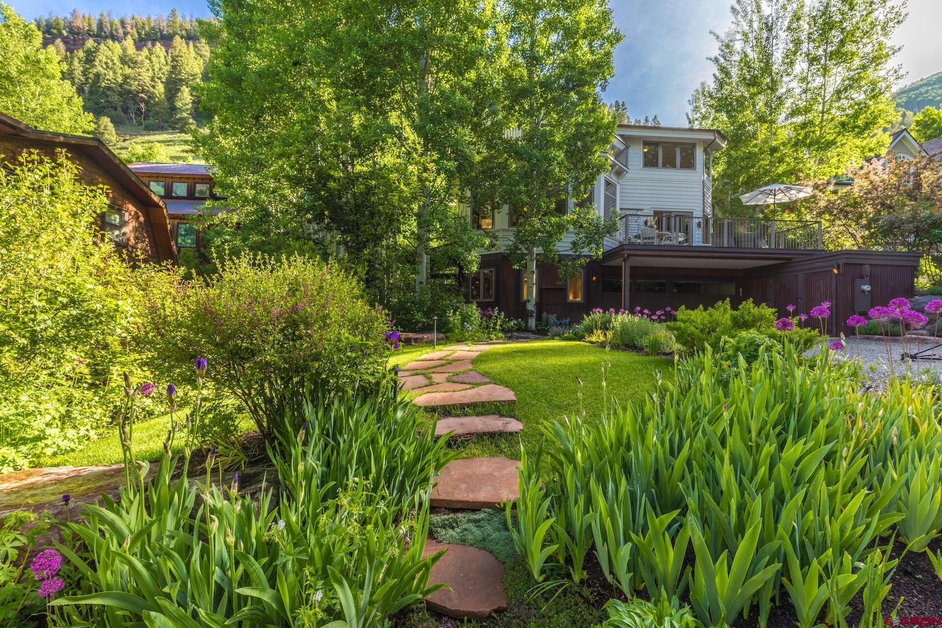 Immerse in the tranquility of this hard-to-find secluded home, nestled beyond a 1-lane bridge on an oversized lot. Steps away is the only creek running through town, its gentle sound a constant reminder of the sanctuary that awaits you. Relax in a lush, cascading flower garden surrounded by towering aspen trees providing a sense of privacy & seclusion. A roomy, gated backyard is perfect for pets, dinner parties, or a game of croquet. Inside is just as inviting. Explore creativity in the flex room & study. The meditation deck, with its commanding views of snow-capped mountains, beckons to soak up the peace & quiet surrounding you. A supersized 3+ car garage has lots of storage. Whether looking for solitude or shared adventures, experience the good life in this hidden mountain oasis.