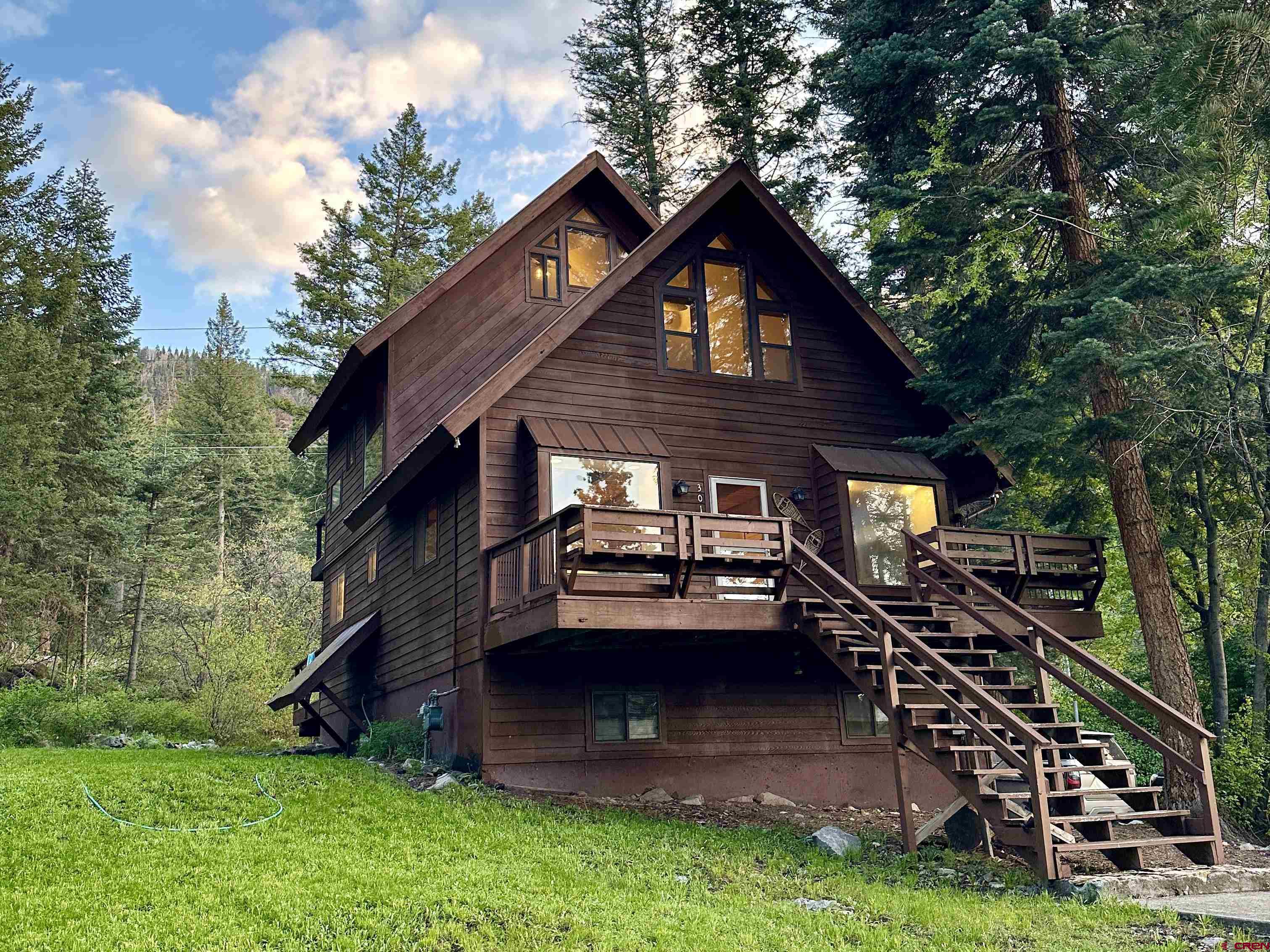 This amazing mountain home is located just outside of the city of Ouray (1.7 miles to the pool and downtown). Move in to this stunning residence, or utilize it as a vacation home/short-term rental. Located in Ouray County, just across the county/city line, this comes with a TRANSFERABLE SHORT TERM RENTAL PERMIT! Having this transferable permit opens up so many options for the next owner, as there is currently a 5-year waiting list in Ouray County to access a new short term rental permit. The permit for this property is #007. The property is entirely turn-key, and can be immediately utilized as a short term rental if desired. Tucked in amongst towering pine trees, this property provides privacy and and an amazing, peaceful environment. Enjoy the outdoors from the front deck, back deck, or private balcony deck off of the primary room. Completely renovated top to bottom in late 2022! The home, which is being sold furnished, features all brand new beds and bedding, luxe linens and towels, a fully stocked kitchen, a cozy pellet stove, and so much more. The loft bedroom has tons of natural light from 10 ft windows and a king size bed, a cozy leather lounging chair, and beautiful views. The primary bedroom features a king size bed, TV, a vanity & sink, and exclusive access to a private upper balcony deck via wall-to-wall sliding glass doors. Wake up looking straight out into the stunning wilderness! The "bunk room" is spacious and has two queen beds and a set of twin bunk beds. This room also has amazing 10 ft windows to gaze out into the pines from. The lower level bedroom features a plush queen bed and is on the walk-out basement level. There is a full bathroom on the walk-out basement level, a full bathroom on the upper level near the primary and bunk rooms, and there is a half bath on the main level. The chef's kitchen is fully equip with everything you may need, and features a brand new high end 36' ZLine oven/range. Solid granite countertops and a modern backsplash bring both form and function to the kitchen. There is high end cutlery, professional grade pots and pans, and plenty of bakeware and chef's tools included. Sliding glass doors walk out to the back deck from the dining/kitchen area. The living room features a 55' TV, a cozy pellet stove, amazing window seats, and a high end italian leather couches. The ceilings in the living room and primary room are tongue and groove aspen, providing an amazing cozy-cabin feel. There is another small living area on the walk-out basement level complete with a wet bar, beverage refrigerator/freezer, a microwave, and more. This space has been a 1B/1B apartment in the past, and could easily be returned to that configuration with a few simple adjustments. It also has private exterior access. There is a full bathroom on the level of the home that features the primary bedroom and the bunk room. Brand new granite vanities have been installed in this bathroom and the primary bedroom. There is another full bathroom on the walk-out basement level, and a 1/2 bath on the main level near the living room.  The property is ideally located for those seeking peace and quiet but do not want to be far from town. Easily drive in for dinner and a soak at the hot springs, and then retreat to the serene peace that the woods provides. Ouray is known as "The Switzerland of America" and attracts visitors from near and far, year after year. Don't miss out on all that this stunning home and community have to offer!