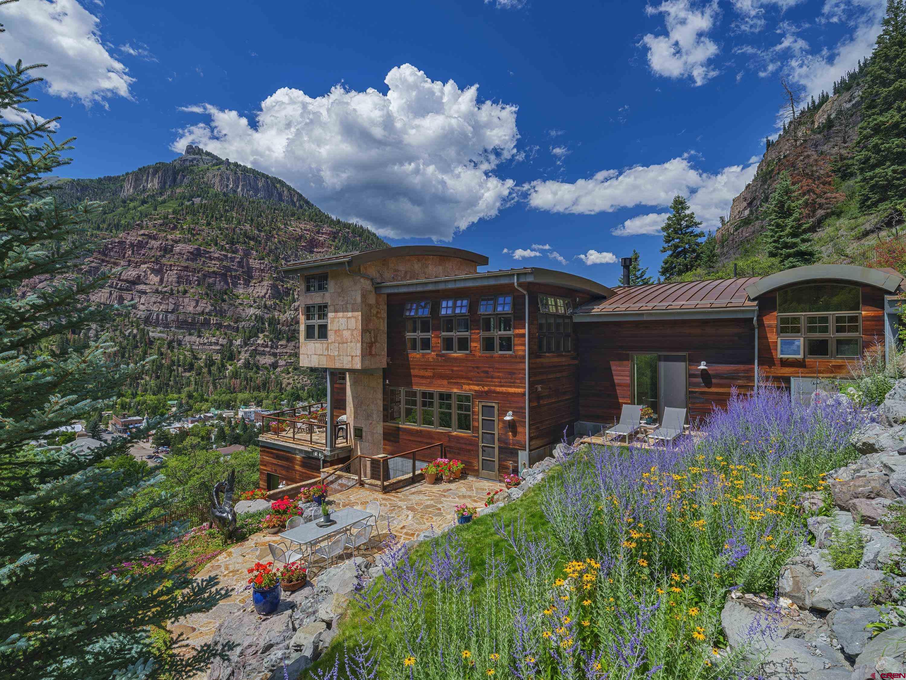 Custom designed luxury home situated on the side of the mountain overlooking Ouray. Boasting over 4,000 square feet, this remarkable, multi-level residence features thoughtful architectural details that complement the majesty of the surrounding area, while floor-to-ceiling windows capture the restorative beauty of the San Juans. Clean lines, rustic textures and natural materials set the tone of the interior spaces that rest within this Ouray Perimeter trail side property. With some of the best views in Ouray, 433 Hillcrest is one of the most desirable homes in the region. The large, open living room, with rich hardwood floors, invites one to relax by the antique Shenandoah fireplace, admire its stunning architecture and dramatic views of the surrounding vistas. A well-appointed gourmet kitchen, complete with a fantastic 6 burner AGA range and adjacent great room make entertaining simple and easy. The main bedroom wing offers amazing views, a spacious dressing room and its own private deck with custom built wood hot tub and wonderful seclusion from the main residence.  Additional amenities include hi-speed fiber optic cable, a Bluetooth enabled sound system installed throughout home and wireless app control of all landscape irrigation, spa hot tub functions and monitored alarm system.  All outdoor decks and driveway pad have induction heat. Created and drawing deeply from the history of Ouray, reflected in the way the home is designed on its spectacular lot, with pick-ax cross windows, a mine shaft feel to the central tower and finally, the gentle curves of the roof creating a serene contrast to the peaks. The architectural curves exude a quiet strength with their natural flow and showcase the idyllic mountain setting and expansive outdoor living spaces.