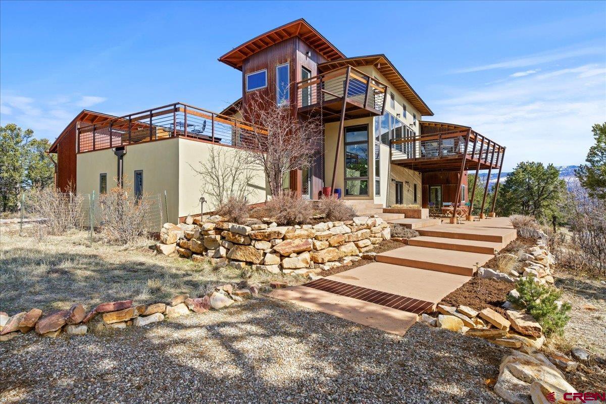 Spectacular is the only way to describe this contemporary masterpiece sitting on 9.3 acres adjacent to the ever desirable Log Hill Village. Patios, decks and huge windows take full advantage of the panoramic views of both the Cimarrons and San Juans. The main floor features an extremely well designed open floorplan that includes the great room, dining room, and, the heart of the home, the kitchen. Rung with windows on the south and west, the natural light in this space is remarkable.  The curved beams in the great room are architecturally unique and add an incredible dimension to this wonderful space. Entertaining is trouble-free as guests gather around the island or wander out to the decks and enjoy the quiet and the views.  The kitchen is home to unique wood, granite and stainless countertops, a walk-in pantry, a huge Kitchen Aid range/oven, microwave and built-in refrigerator, a wonderful corner sink and unique contemporary lighting. Not to be missed, as an added bonus in this space, is the charming loft over looking the Great room. A wonderful place to retreat from the world with that first cup of coffee in the morning or a well deserved glass of wine at the end of the day. The Master suite is positioned to take full advantage of the views to the south, east and west. Multiple closets plus a very large walk-in closet provide room for just about everything. The master bath features a wonderful soaking tub, separate shower and the washer and dryer which makes so much sense! No hauling the clothes from place to place!  And the downstairs!! It is designed with specific uses that are so important. A craft/mud room coming in from the garage is complete with a dog wash and direct access to the dog run. Perfect! The family room with its wood stove is ideal for watching the game or having a special space for grandchildren to play. The guest bedrooms insure privacy for special visitors and an extremely large office makes work time more than enjoyable. A patio off the family room and one guest room is accented by the surrounding pines, views and the quiet that 9.3 acres affords. A very large solar array delivers more than enough hot water for the home. The heated garage with its floor drain is a wintertime bonus! If horses are in the picture, they are allowed! All in all, a stunning contemporary showpiece artfully designed to take full advantage of its amazing Colorado setting.