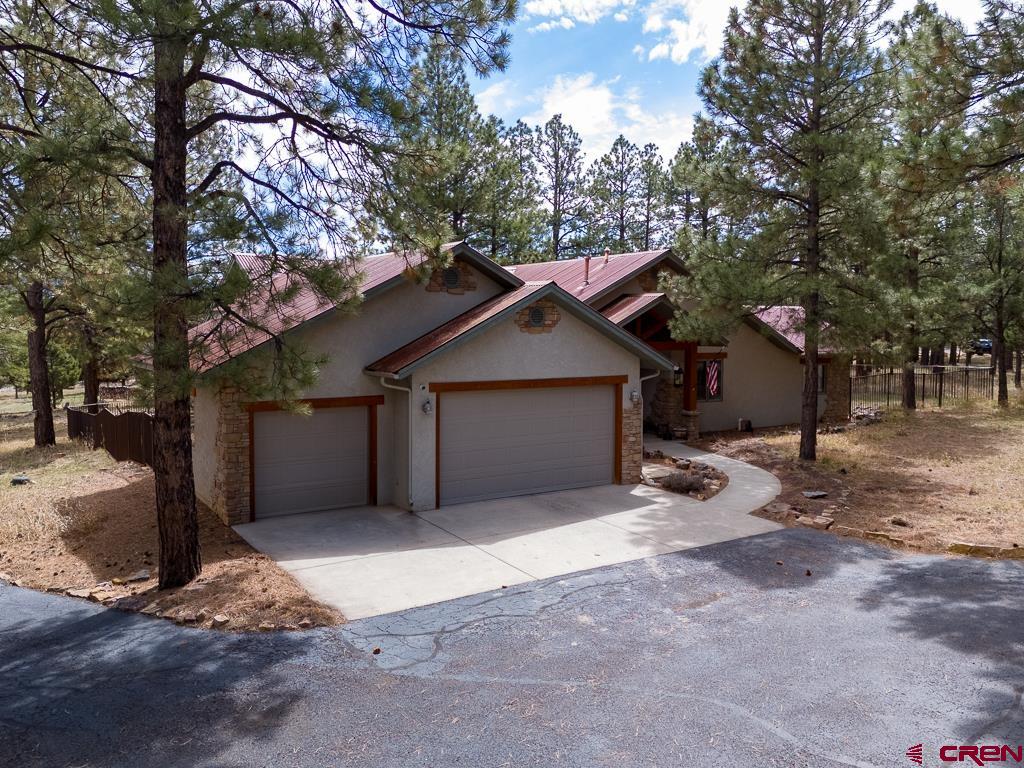 Located 15 minutes from downtown Ridgway, 45 minutes from Telluride and 30 minutes from Montrose and Ouray, sits a beautiful, single level 2,081 SQ FT custom home on a peaceful .96 acre wooded lot in the beautiful Divide Ranch and Club golf community. The paved driveway leads to a house with many custom features that truly make this place special. As you walk in you are greeted by the open concept living area that is perfect for entertaining with a fabulous wet bar, double sided gas log fireplace, stunning hardwood floors, vaulted ceilings and lots of natural light coming from the many windows.  Arched doorways throughout the house adds class to the home. There is a covered patio off the living room. The patio is east and south facing with views of the Cimarrons, and the back yard. The back yard is fully fenced with a tall rusty iron fence.  The kitchen has granite countertops, plenty of cabinets and countertop space, a large island and pantry. The dining room area is open to the kitchen and living room and has plenty of room for a large table. The guest wing features a shared bathroom and two bedrooms. The south facing bedroom has a private patio that connects to the backyard entertaining area. The primary wing has a large bathroom with two vanities, soaking tub, a large floor to ceiling tiled shower, separate water closet and walk in clothes closet. There is also a quiet patio with a hut tub over looking the Cimarron mountain range, stone firepit and towering Ponderosa pine trees. The laundry room has great storage and leads into the 3 car garage. A golf membership comes with this offering. This home is beautiful and ready to move in!  Come see it for yourself.
