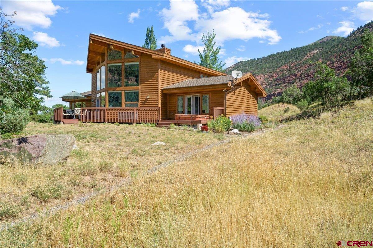 Conveniently located halfway between Ouray and Ridgway, this impressive 4,027 square foot cedar frame home sits on a rise amid five acres of Ponderosa pine, oak and juniper. With commanding views of both Whitehouse Mountain and Mount Abram, the home is a certified Lindal design, built and customized by well-known local contractor, Mark Woodruff. With four bedrooms and four bathrooms, it features a large two story great room with an expansive wall of windows, plank ceiling, wood burning fireplace, and a convenient updated kitchen. The home's exposed wood beams, hardwood floors and stone finishes reflect both a mountain and contemporary style. The long wood deck with jacuzzi offers remarkable views and ample space for outdoor entertaining. Upstairs you will find a loft office/craft space with wonderful light overlooking the great room and views to the west plus a bedroom and bath for guests.  And the lower level! Home to a 950 square foot finished basement that could be used as a game or media room or even extra guest accommodations. There is also a shop and half bath. The heated garage is more than welcome in the winter and the electrical hook-up near the garage for an RV and a convenient shed for storing just about anything are added bonuses. A warm, inviting home that guarantees many years of enjoyment in this special part of the world that is Ouray County!