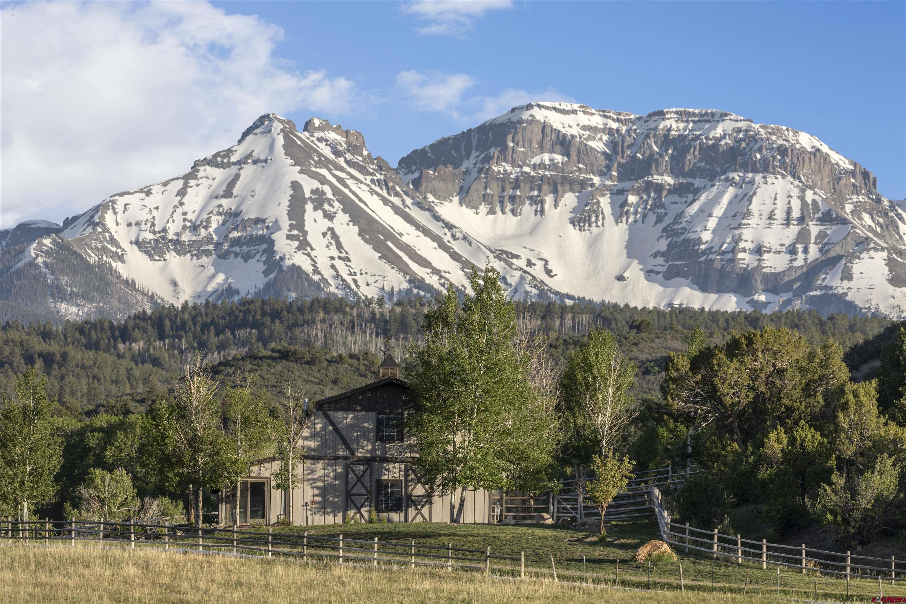 Perched in a picturesque valley above Ridgway, this unique property offers expansive views of the Cimarrons, Ouray Valley, and Sneffels range. This private enclave is just outside the charming town of Ridgway and boasts abundant wildlife that calls the land home. A resident elk herd of over 100 elk roams the property, along with coyotes, foxes, mule deer, and a variety of bird species, creating an exceptional natural setting.  The land benefits from Dallas Creek water rights, ensuring lush green pastures that attract both wildlife and offer a serene environment for relaxation or recreation.  The property features a 3-bedroom, 2-bathroom house, perfect for immediate occupancy or as a starting point for a spectacular remodel. Additionally, there is a three-car garage with a studio apartment above, ideal for multi-generational living, an art studio, or rental income.  Close to Ridgway, you’ll enjoy access to excellent restaurants, shops, farmers markets, and vibrant community events, all while being surrounded by nature’s beauty.