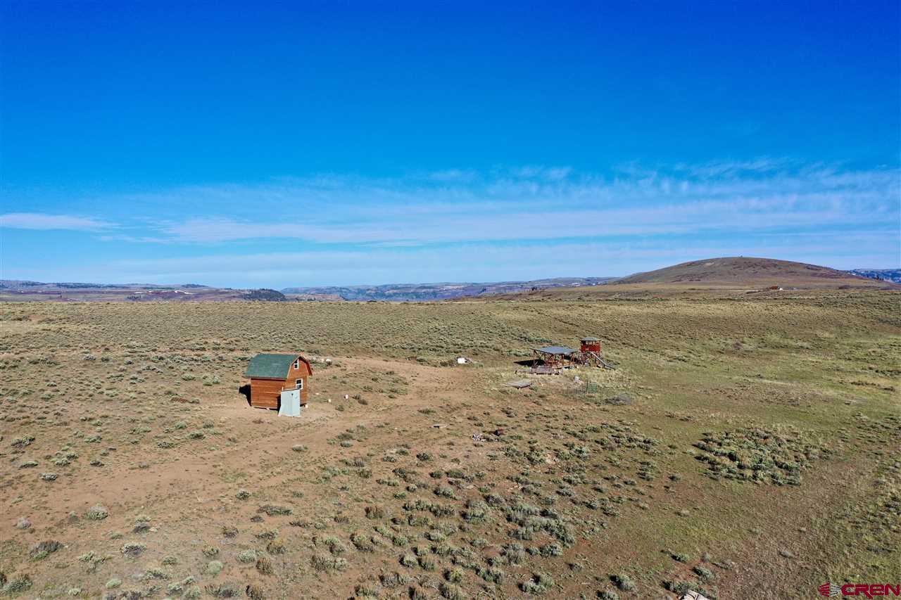 360 degree views from this 78 acre cabin site. Seller has built a shed/sleeping loft on the property. There are two decks for RV's to park by. One is covered & the other is open. Perfect RV set-up for a summer playground. ATV/moto-cross course on the property, seasonal spring-fed pond, perfect for a hunting camp or summer cabin. Property is accessible in the winter via snowmobile or track vehicle. Nearby property has good well & septic, as well as solar & wind power set-up & generator. Just 5 minutes from Blue Mesa Lake.