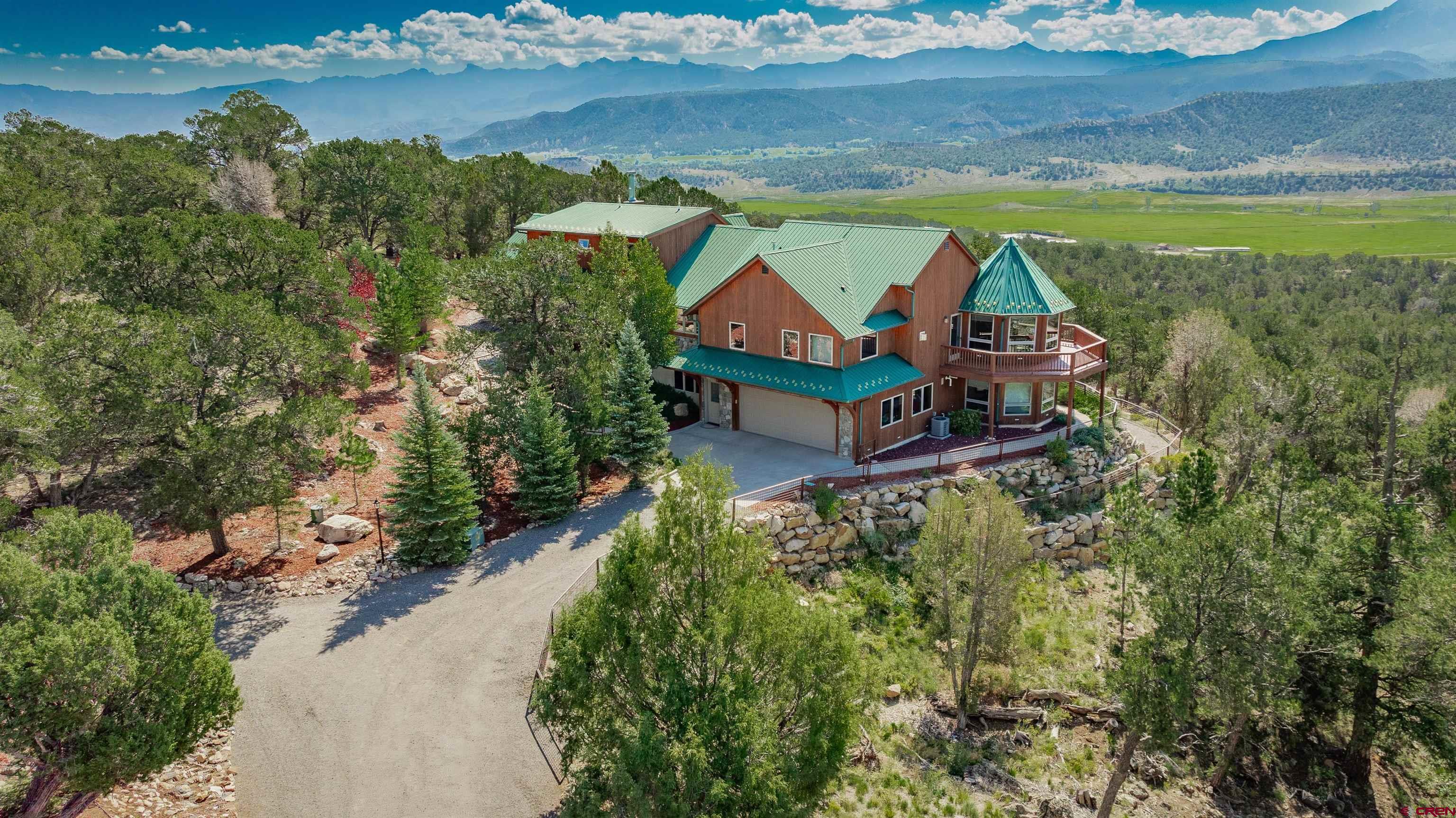 This beautiful 5 bedroom/6 bathroom mountain home is situated on 4.18 acres in the desirable Pleasant Valley Vista overlooking the famed Double RL Ranch. An 1800 square foot deck faces the San Juan Mountain range with spectacular and incomparable views of Mount Sneffels and the Cimarron range. The home has 5676 square feet of living space. The main level houses the kitchen, great room, dining room, office, extra full bathroom with jacuzzi, master bedroom, and elevator. The gourmet kitchen is an open-concept with granite counter tops and a bar that seats 12 – 14 people. Custom cabinetry and Brazilian hardwood floors accent the large main kitchen with a buffet on one side and a wet bar with a wine cooler and separate ice maker on the other. The great room has a large double-sided stone fireplace and beautiful wood trimming the upper windows across the entire main floor. The master bedroom is 1433 square feet with central air conditioning, a fireplace, and picturesque views of the valley and mountains along with two walk-out doors to the deck. A spacious bathroom with garden tub completes the huge master suite. Multiple large windows provide plenty of natural light, with new blinds installed for privacy. On the upper floor, there are two bedrooms with ample storage in the closets and a full bath. On the ground floor, there are two additional bedrooms, a full kitchen and 2½ bathrooms. This spacious lower level is well-designed for a separate living quarter, perfect for in-laws, teens, or guests. Two new furnaces, one with radiant heat, have recently been installed. This fire- mitigated property is filled with mature trees including blue spruce, pine, and aspens with a drip system for watering over 3 acres and an inground sprinkler for the landscaped front entrance. Relax and soak in the peaceful views in the 6-person outdoor hot tub. Perfectly situated for the outdoor enthusiast, this home is only 10 minutes from quaint downtown Ridgway with biking trails and shops; 17 miles to Ouray with the Hot Springs, jeeping, hiking, and ice-climbing; and only 30 minutes to Telluride for world-class skiing, mountain biking, golfing, concerts, and seasonal events. This dream home is perfect for a large family or as a second base camp home. You need to see this property to fully appreciate it. Schedule an appointment today. This special piece of heaven could be yours!
