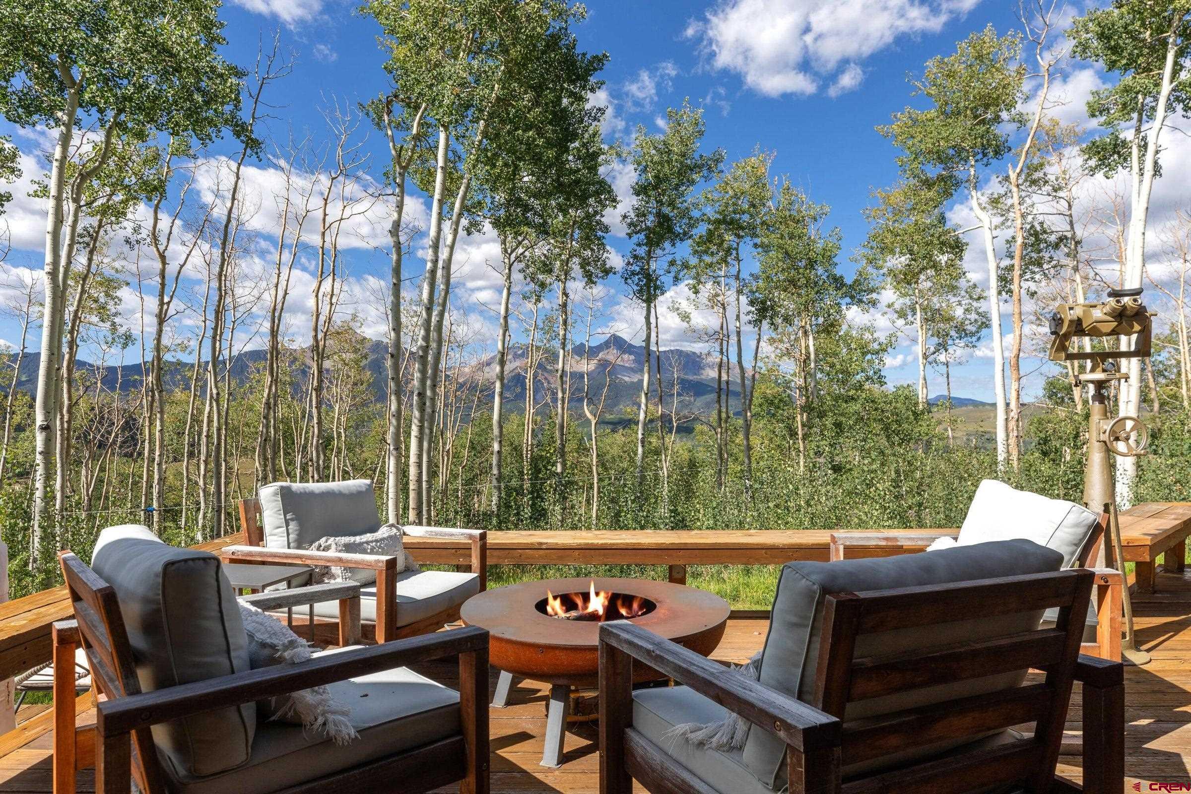 Arguably one of the top 2-3 sites in the highly sought after Ski Ranches neighborhood and nestled on a serene 2.37 acre knoll top, this exceptional property offers unparalleled privacy and breathtaking views, with the added luxury of being adjacent to 10 acres of pristine open space. Experience sweeping views from Palmyra, to Sheep Mountain, with Sunshine and Mt Wilson framed front and center, including corridors that travel down valley with year round sunsets. Floor-to-ceiling glass walls wrap around the property and seamlessly integrate the stunning natural surroundings, bathing the interior in natural light and providing uninterrupted vistas from every room. The bright and sunny interiors create a warm and inviting atmosphere, while the open-concept living area is perfect for gathering  Cozy up by the wood-burning fireplace during chilly evenings, and revel in the beauty of nature just outside your door. Generous outdoor living spaces and extra flex spaces, ideal for home offices, playrooms, game rooms, or additional guest accommodations round out the space. With a main home and a convenient guest house, this property is perfect for hosting family and friends. Located just five minutes from the Mountain Village and the world class Telluride Ski Resort, you'll have all the best outdoor activities at your fingertips. Whether you're enjoying a quiet morning coffee or entertaining guests, the panoramic views create an ever-changing backdrop of beauty. This property is a true private sanctuary, combining modern design with the tranquility of nature, making it the perfect mountain dwelling. Don't miss the opportunity to own a home on the best lot in the neighborhood. Schedule a viewing today and experience the magical setting of this mountain retreat for yourself.