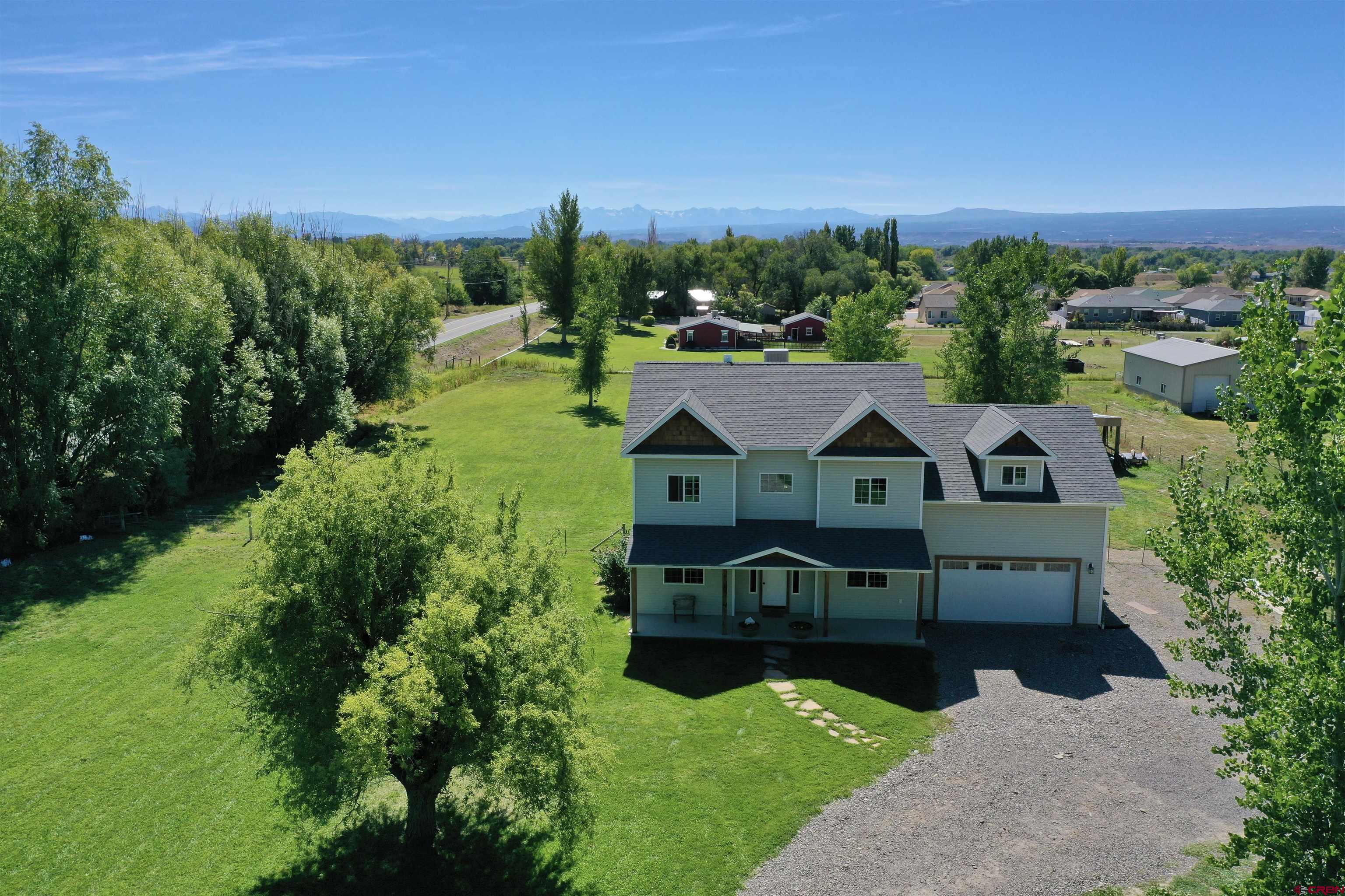 The opportunity you've been waiting for is here just in time...take a look at this beautiful 2017 built, 5 bed, 3 bath, 2,237 sqft farmhouse style home on just over 2 irrigated acres in a very convenient location just beyond Montrose city limits! Sitting on the corner of Little Way this Equestrian Acres home offers green grass and large mature trees around the perimeter of the property strategically placed to ensure the privacy is maintained. The south-facing mountain views and natural light fill the home in every room. Plenty of space outside to still add a workshop, detached garage, RV/Toy storage, etc. Have you been thinking about having a horse or other animal on your own property for easy access and convenient caretaking...all options here! Not to mention, just around the corner to the north, you've got amazing access to public lands with trails in every direction for all types of recreational users and activities. Even top notch fishing in the beautiful Gunnison Gorge just below the Black Canyon of the Gunnison National Park. As you approach the home down the tree-lined drive the hand hewn oak posts on the front porch and cedar shakes in the front gables make for great curb appeal. Inside the foyer there is space to kick your shoes off and make your way to the living room, kitchen, bathroom, or the office/bedroom/flex room all right on the main level...a very efficient use of space! Upstairs there are 5 bedrooms, one of which is a very large and spacious room above the garage that could be utilized as a bedroom, workout room, home office, movie room, craft room, or whatever your need may be. A large full bathroom is right off the upstairs hallway and at the other end of the upper level is the primary suite with mountain views, two closets, and a beautiful tile surround dual headed glass shower enclosure. Call today for your private showing so you can take in all that this stunning Western Colorado property has to offer!