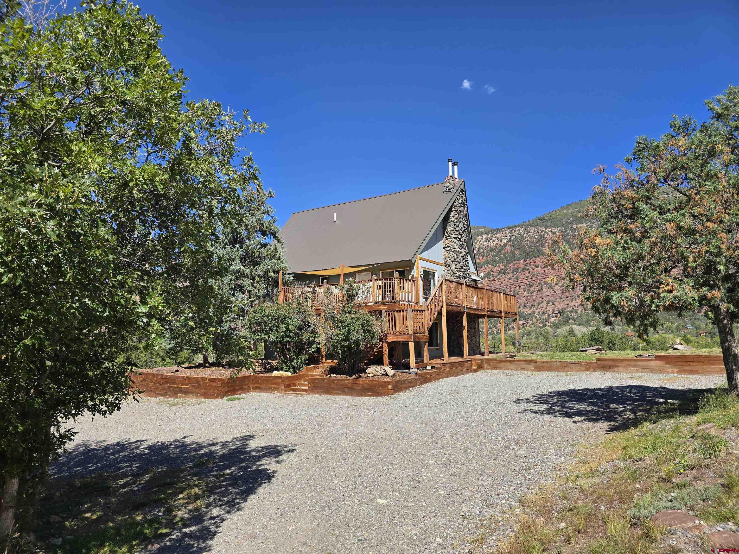 PRICE IS NEGOTIABLE   Are you looking for a house that is instantly ready to go for you?   This one of a kind home offers a turn-key solution to your dream of owning a home with substantial earning potential while allowing you to live in the San Juans.     This house was  a diamond in the rough in its past life, but the current owners have painstakingly converted it into a very profitable, beautiful home.  Located in the quiet neighborhood of Idlewild, the home sits exactly between the towns of Ouray and Ridgway and is only 45 minutes to world class skiing in the town of Telluride.   Your new home sits on 2.2 acres of stunning prime Colorado land with red cliffs soaring above you to the East and to the West, views of Mt. Abrams to the South and gorgeous Alpenglow skies to the North with the sunsets.  The roof, windows, floors, plumbing, septic, electrical, appliances, heating and anything else you can think of, have all been upgraded, rebuilt, replaced and loved.   For those that need a little entertainment in the summer, watch the soap operas unfold with the coming and goings of the campground just below the house.    The main unit consists of the two upper levels, beautifully remodeled with a rustic and cozy charm.  The main level boasts two large bedrooms, a full bath and a large open concept living/kitchen area with a vaulted ceiling featuring an 80in TV nestled above the floor-to-ceiling stone fireplace with a wood burning stove as well as a large wrap around deck to enjoy outdoor dining and  stunning views.  Take a walk up the hand crafted stairs to the third floor and the  huge master suite with a private loft and natural stone shower.  This unit has always been used as a Short Term Rental (STR) and the license is transferable to the new owner.  There are currently 260 or more 5-Star reviews for this AirBnb and the calendar is constantly booked well into the next year.   Let this established money maker do all the hard work for you.   The current owner will work with the new buyers to transfer all existing reservations to you.  All furniture and supplies needed to operate as an STR are available.  Downstairs you will find a separate 1 bedroom, 950 sqft home that has also been remodeled, boasting a large master bedroom, large custom shower and a wood burning stove that will leave you relaxed on a cool winter evening.  This unit is currently leased long term, but would make for a great owner's quarters as well.   Live in one unit and let the other pay your mortgage for you.  Don't overlook this one - homes that pay for themselves in this area are hard to come by! Seller offering a credit for deck work.