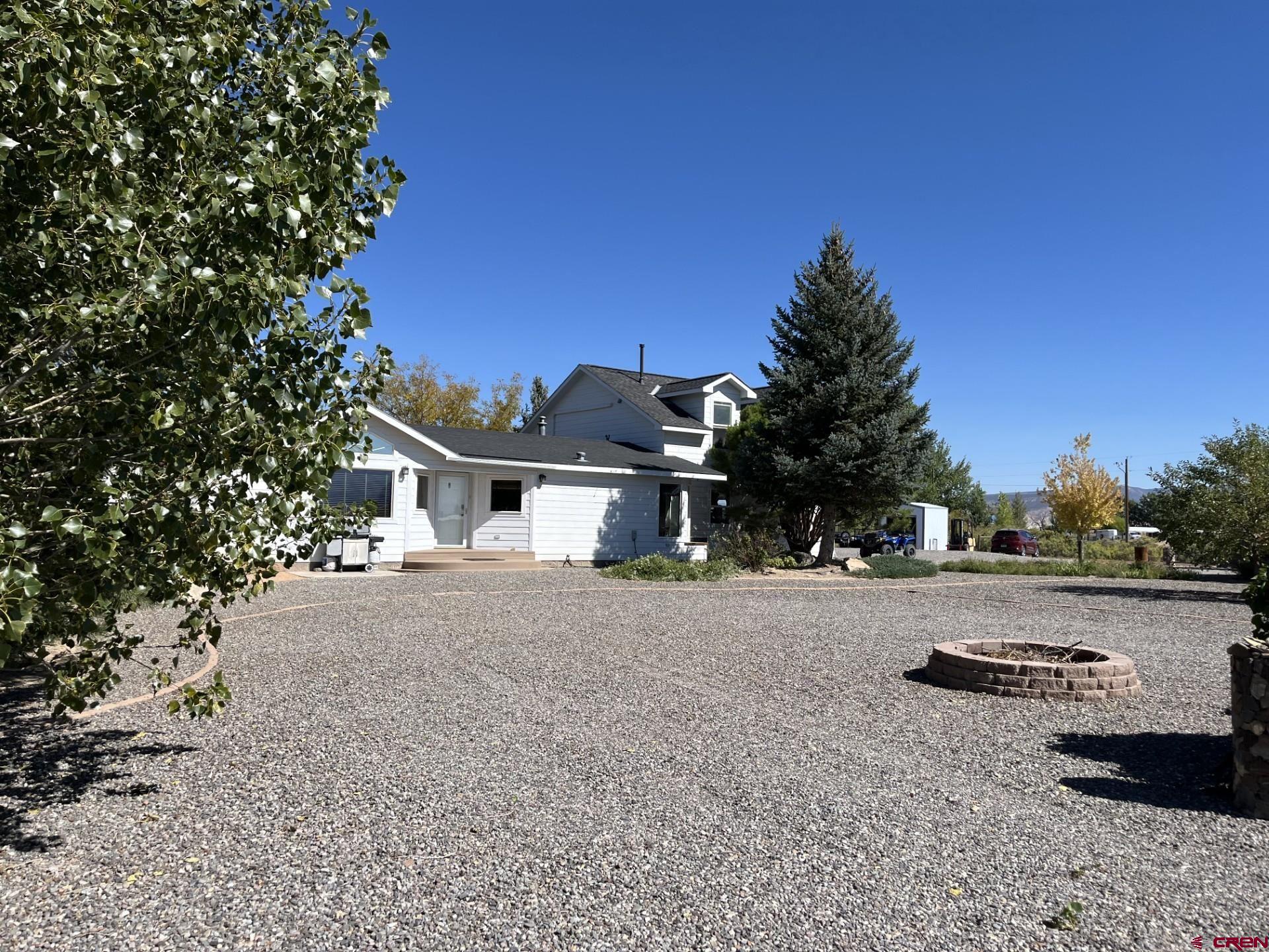 This home has it all! It is a 2002 manufactured home on a permanent foundation with the title purged, and a foundation wall for a clean look. When the previous owners added the stick built double garage, both the home and garage were completely resided to match. The present owner then added a second story to the house, adding 595 square feet, for a total of 2,150. The current owner has great construction skills  Upon purchase, he basically went through the house and made all of his desired changes with a great deal of thought and skill. On the main level, new flooring ( carpet and tile) has been added, in addition to both downstairs bathrooms being remodeled. There is a primary suite on this level that was enlarged and created from a smaller room to have a lower level primary suite, a 3/4 bath with beautiful tile work, flooring, and a two sink vanity. On this main floor there are two more bedrooms and a remodeled full hall bath. One of those bedrooms  was used as a craft room, so there is extensive shelving and storage space. It could be another bedroom or an office, as well.  The living room is bright and sunny ,with a propane fireplace and lots of built in  shelves. The dining room is large and can accommodate large pieces  easily. The kitchen has also been remodeled and is very functional. Around the corner is the laundry room . Let me just say that if there was any place to put storage closets or shelves- this home has them! Now, the fun part! Upstairs in the additional 595 square feet , there is a room of many uses. It is currently an additional primary suite, but could also be a man or  woman cave. it has two dormer windows, one has a piece of exercise equipment and the other has a desk. There is a long closet built into a side wall, with a door at each end for easy access, along with two other closets. There is a great 3/4 bath, a two sink vanity...and wait for it... a built in bar area that includes a small refrigerator!  No going downstairs in the middle of Monday Night Football or a movie to get a snack or something to drink! Outside is a three sided shed for just about anything, in this case, equipment. It is 408 square feet according to the Assessor. There is also a smaller metal shed.  If you have toys and vehicles, I don't think you could run out of room to put anything!  This house was built to enjoy life, along with the 6+ acres and the never ending views!  ***Please see Associate Documents for Inclusions and Exclusions***