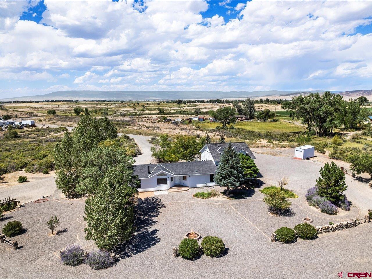 This home has it all! It is a 2002 manufactured home on a permanent foundation with the title purged, and a foundation wall for a clean look. When the previous owners added the stick built double garage, both the home and garage were completely resided to match. The present owner then added a second story to the house, adding 595 square feet, for a total of 2,150. The current owner has great construction skills  Upon purchase, he basically went through the house and made all of his desired changes with a great deal of thought and skill. On the main level, new flooring ( carpet and tile) has been added, in addition to both downstairs bathrooms being remodeled. There is a primary suite on this level that was enlarged and created from a smaller room to have a lower level primary suite, a 3/4 bath with beautiful tile work, flooring, and a two sink vanity. On this main floor there are two more bedrooms and a remodeled full hall bath. One of those bedrooms  was used as a craft room, so there is extensive shelving and storage space. It could be another bedroom or an office, as well.  The living room is bright and sunny ,with a propane fireplace and lots of built in  shelves. The dining room is large and can accommodate large pieces  easily. The kitchen has also been remodeled and is very functional. Around the corner is the laundry room . Let me just say that if there was any place to put storage closets or shelves- this home has them! Now, the fun part! Upstairs in the additional 595 square feet , there is a room of many uses. It is currently an additional primary suite, but could also be a man or  woman cave. it has two dormer windows, one has a piece of exercise equipment and the other has a desk. There is a long closet built into a side wall, with a door at each end for easy access, along with two other closets. There is a great 3/4 bath, a two sink vanity...and wait for it... a built in bar area that includes a small refrigerator!  No going downstairs in the middle of Monday Night Football or a movie to get a snack or something to drink! Outside is a three sided shed for just about anything, in this case, equipment. It is 408 square feet according to the Assessor. There is also a smaller metal shed.  If you have toys and vehicles, I don't think you could run out of room to put anything!  This house was built to enjoy life, along with the 6+ acres and the never ending views!  ***Please see Associate Documents for Inclusions and Exclusions***