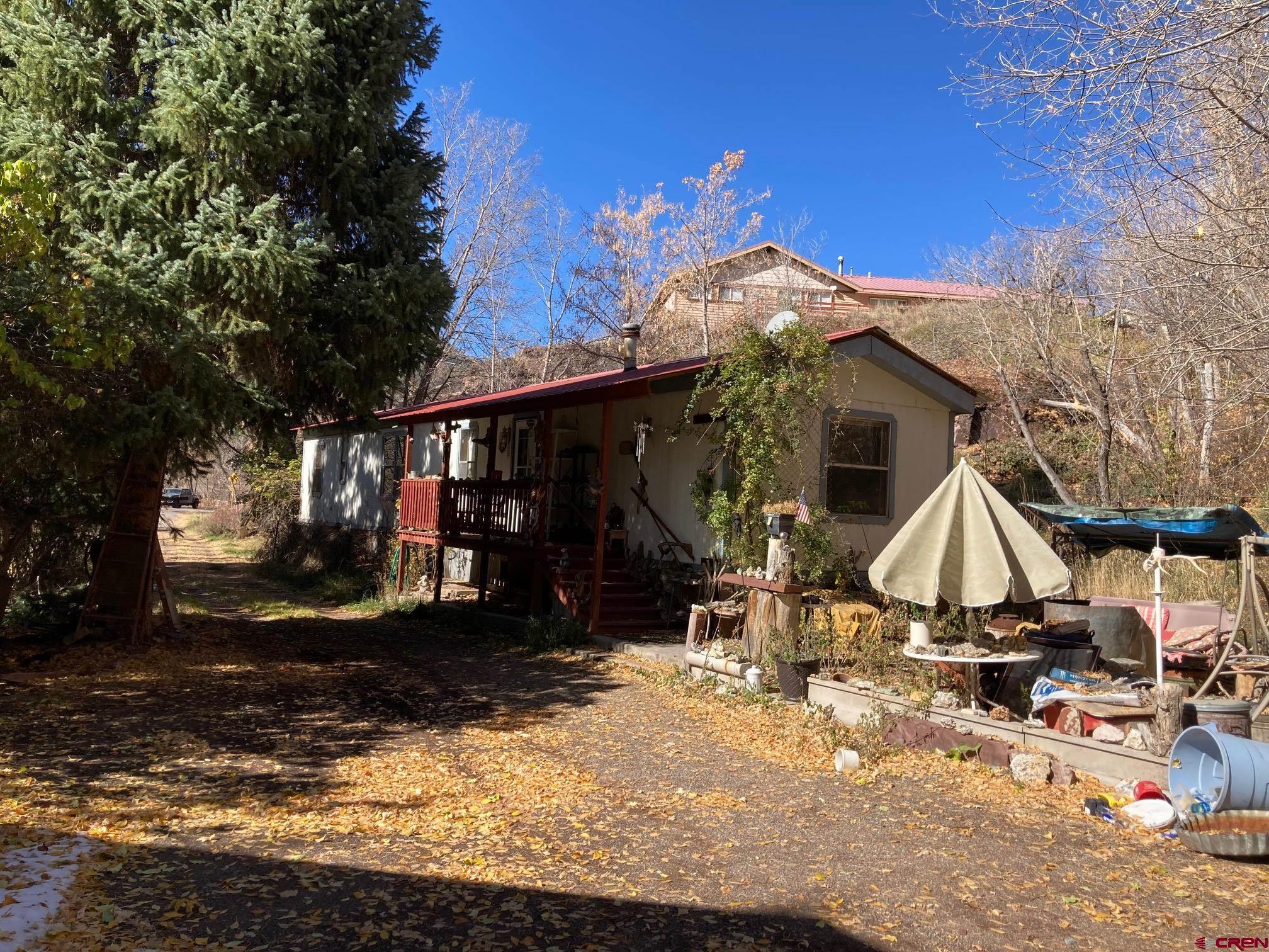 Incredible 2-Acre Property Just Outside Ouray – Your Mountain Dream Awaits! This unique, nearly 2-acre property combines privacy, space, and all the perks of living in Ouray, Colorado’s mountain paradise! Located on the north edge of town yet just outside Ouray’s boundaries, this site offers a rare blend of convenience and seclusion. With essential utilities, including San Miguel Power, Black Hills Natural Gas, and – best of all – Town of Ouray water and sewer services, this property ensures hassle-free living without the need for a septic system. Historic Charm and Endless Potential Lovingly owned by a cherished local family, this property exudes a connection to Ouray’s rich mountain heritage. Nestled against a wooded hillside, the existing two-bedroom, two-bathroom mobile home features a durable metal roof and a cozy covered porch. It’s move-in ready and offers the ideal base for future dreams! With a hidden drive leading up to stunning sandstone benches overlooking the mountains, this property opens doors to endless possibilities. Consider it as a scenic spot for an RV, guest cottage, or even a future main residence with unparalleled views. Additional Features for Active Mountain Lifestyles Across from the home is a spacious 25’ x 35’ insulated workshop with a full slab foundation and upper-level storage – perfect for storing gear, tools, and equipment for all your backcountry adventures. The expansive, level lawn area, lined with fruit trees and evergreens, invites outdoor living and relaxation, while also offering room for expansion and creativity. Ouray Mountain Living with Flexibility and Vision Whether you're looking for a forever home, a seasonal retreat, or a promising investment property, this Ouray gem has all the essentials. Dreaming of designing a custom mountain home? Live in the mobile home while planning your ultimate residence on this gorgeous acreage! Make this your launchpad for exploring Ouray’s endless hiking, backcountry skiing, and breathtaking scenery. Schedule your visit today and discover why this Ouray property is the perfect blend of natural beauty, privacy, and future potential. Embrace the mountain lifestyle and make this special place your own!
