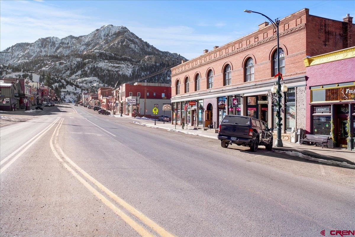 Discover the perfect blend of historic charm and modern luxury in this loft style condo located smack dab in the center of Ouray, Colorado. This fully-updated historic gem offers easy walking access to all that Ouray has to offer.  Step inside to an inviting, open layout featuring high ceilings, exposed post and beam construction, and exposed brick walls that exhibit timeless character. The kitchen, dining, and living areas flow seamlessly, showcasing upgraded, newer finishes throughout: granite countertops, hickory cabinets, engineered hardwood plank flooring, travertine tile, efficient forced air heating and air-conditioning, and double-pane tilt-in windows.  Relax in the cozy living area by the free-standing gas log stove.  The entire building was renovated in 2010 with modern systems, including updated plumbing, electrical, insulation, fire suppression, and an elevator. High speed fiber internet is in the building.  This unit includes its own private garage and a roomy, secure storage room, for effortless mountain living.  Units in this building have a strong short-term rental history.