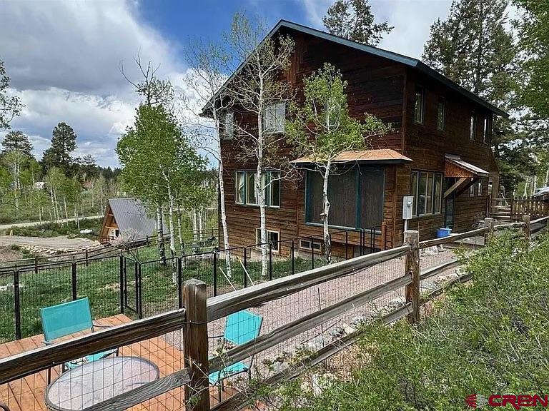 Hurry and grab this opportunity as this home is listed at a great price!!! This home is currently listed with the lowest price per sq ft in Ouray County (Stick Built) at $246.44 per sq ft - The average price per sq ft in Ouray County is $584.   Nestled in the Aspen trees in Elk Meadows Estates, this home is a wonderful blend of a mountain cabin with modern touches. It features 3 bedrooms, 2 full bathrooms, and one half-bath in the main two floors of the home. There is also a full, finished walk out basement. Half of the basement has been converted to a separate living space with a full bath, large closet, and ample storage. Having its own separate entry to a private driveway and parking area as well as individual access to the fenced yard, this space has the potential for a multitude of uses. The home offers ample storage inside and in the large shed outside. Highlights include granite countertops, newer appliances, hardwood and tile flooring with warm wood trim, and a large Primary Bedroom with a 5 piece Bath that must be seen to be fully appreciated. Numerous windows provide an abundance of light and breath taking views in each direction. The large fenced yard is perfect for children and pets, and the protected garden space and landscaping compliment the natural setting. Passive solar on the south wall keeps heating costs low in the winter and Fiber Internet keeps you connected. Elk, deer, turkey and an abundance of other wildlife are regular visitors to the property and surrounding neighborhood. This 1 acre parcel is just a 15-minute drive to Ridgway, 1 hour to Telluride, and under 2 miles to National Forest access, offering trails for cross-country skiing, snowshoeing, and snowmobiling in the winter, and hiking and camping in the summer. The San Juan Hut system trails can be accessed year-round. Top of the Pines, only 3 miles away, offers sledding, cross-country skiing, and snowshoeing in the winter, as well as hiking, camping, and open spaces for walking your dog in the summer. Come enjoy the best of Colorado mountain life. This property has income-producing potential as a long-term rental in a high demand rental market. It can be rented as one large rental unit, or the basement studio can be separated out as an independent living space for a second rental. Adjacent 1/2 acre lot available. Owner currently has a VA assumable loan at 3%. Difference would be due by cash.