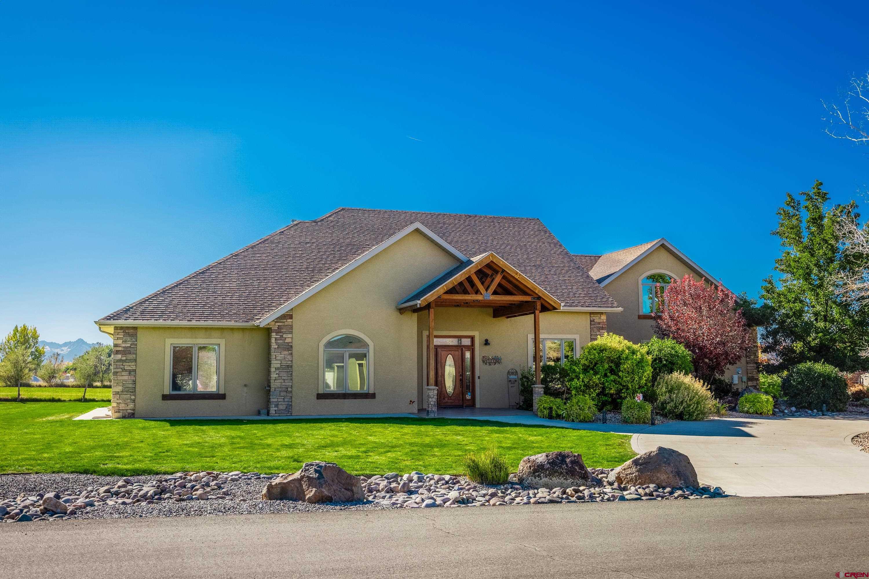 Step into this stunning custom-built home, where you're immediately greeted by a spacious great room with soaring 22' ceilings and panoramic views of the entire mountain range through panoramic windows. Boasting 3,758 sq ft of living space, this home features 4 bedrooms, a dedicated office, and 3 1/2 baths. The living room is a showstopper, with a floor-to-ceiling rock gas fireplace and oversized windows that perfectly frame the breathtaking San Juan Mountain views. The large kitchen is a chef’s dream, complete with a full breakfast bar, sleek black granite countertops, a copper sink, a cookbook niche, built-in oven and microwave, and a 5-burner range top. Beautiful painted, knotty alder cabinets add warmth and character to the space. The dining area offers sweeping mountain vistas, and Australian wood floors flow throughout the home. The large master suite is a luxurious retreat, featuring an ensuite bathroom with custom tile, double vessel sinks, a corner jetted tub, and a step-in glass block shower. In addition to the master, you'll find three more spacious bedrooms, a den/office, and two more full-sized bathrooms. Upstairs, the expansive family room with a wet bar and stunning copper countertops offers ample space for recreation, with room for a pool table, foosball table, or other games. Step outside to the incredible outdoor living space, where you'll find a built-in kitchen area with a BBQ—perfect for entertaining. A private hot tub area enhances the outdoor retreat, and you'll enjoy unobstructed views of Buckhorn, Cimarron, the San Juan Mountain Range, and Horsefly Peak. This home also includes a 3-car garage, lush landscaping, and sits on a 1-acre lot with irrigation water. Lot backs to open property to enhance the feeling of living in the country, yet you are close to all the amenities Montrose has to offer. Built by Sullivan, this property showcases exceptional craftsmanship and quality throughout.