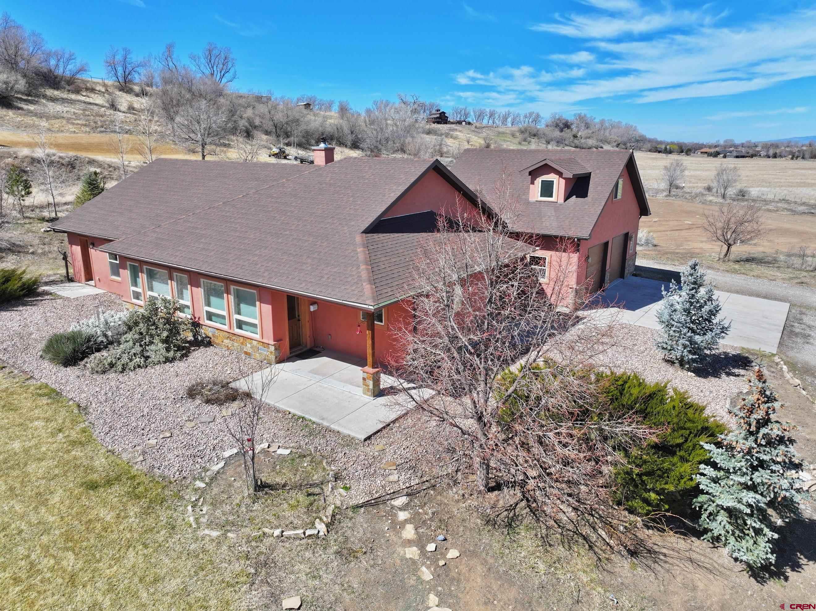 Rare find! This well-designed one-level ranch with a bonus room sits on three spacious acres in a highly sought-after neighborhood southwest of Montrose. Showcasing a warm southwestern flair, this home has it all. Step into a welcoming tiled entryway that leads to a custom kitchen and a bright, south-facing living room. The kitchen includes all appliances, a generous pantry, cork flooring, and a cozy dining nook that connects seamlessly to the living area. The living room features beautiful bamboo flooring and a custom wood-burning fireplace, creating a cozy ambiance. A nearby office, bathed in natural light from its southern windows, can also serve as an additional bedroom. Across the hall, two inviting guest suites share a stylish southwestern-inspired bathroom. At the end of the hallway, the spacious primary suite enjoys abundant southern exposure and boasts two walk-in closets, dual sinks, a separate shower, and a charming clawfoot tub. Above the garage, a newly carpeted bonus room offers breathtaking views of the city lights and mountains—perfect as a recreation space or home office. Adjacent to the garage, the laundry room includes a convenient sink. This home has been freshly painted and features efficient geothermal heating and cooling. The beautifully designed southwestern-style Xeriscaping enhances its unique charm and saves water. Plus, with Elevate internet, working from home is a breeze. A true gem—don’t miss this incredible opportunity! (Some of the photos have been virtually staged)