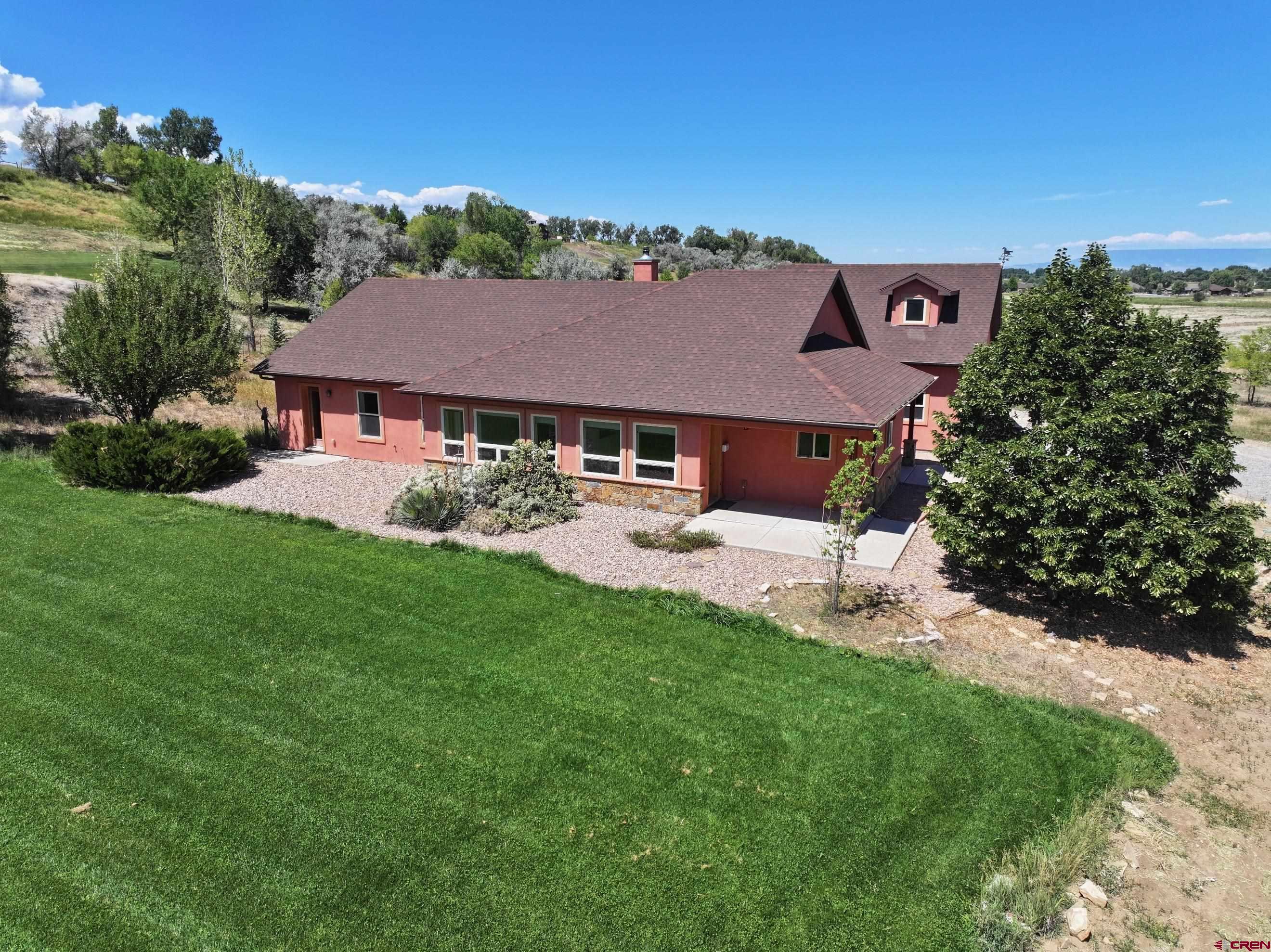 Rare find! This well-designed one-level ranch with a bonus room sits on three spacious acres in a highly sought-after neighborhood southwest of Montrose. Showcasing a warm southwestern flair, this home has it all. Step into a welcoming tiled entryway that leads to a custom kitchen and a bright, south-facing living room. The kitchen includes all appliances, a generous pantry, cork flooring, and a cozy dining nook that connects seamlessly to the living area. The living room features beautiful bamboo flooring and a custom wood-burning fireplace, creating a cozy ambiance. A nearby office, bathed in natural light from its southern windows, can also serve as an additional bedroom. Across the hall, two inviting guest suites share a stylish southwestern-inspired bathroom. At the end of the hallway, the spacious primary suite enjoys abundant southern exposure and boasts two walk-in closets, dual sinks, a separate shower, and a charming clawfoot tub. Above the garage, a newly carpeted bonus room offers breathtaking views of the city lights and mountains—perfect as a recreation space or home office. Adjacent to the garage, the laundry room includes a convenient sink. This home has been freshly painted and features efficient geothermal heating and cooling. The beautifully designed southwestern-style Xeriscaping enhances its unique charm and saves water. Plus, with Elevate internet, working from home is a breeze. A true gem—don’t miss this incredible opportunity! some photos of this listing may include virtually staged amenities, furniture or fixtures.