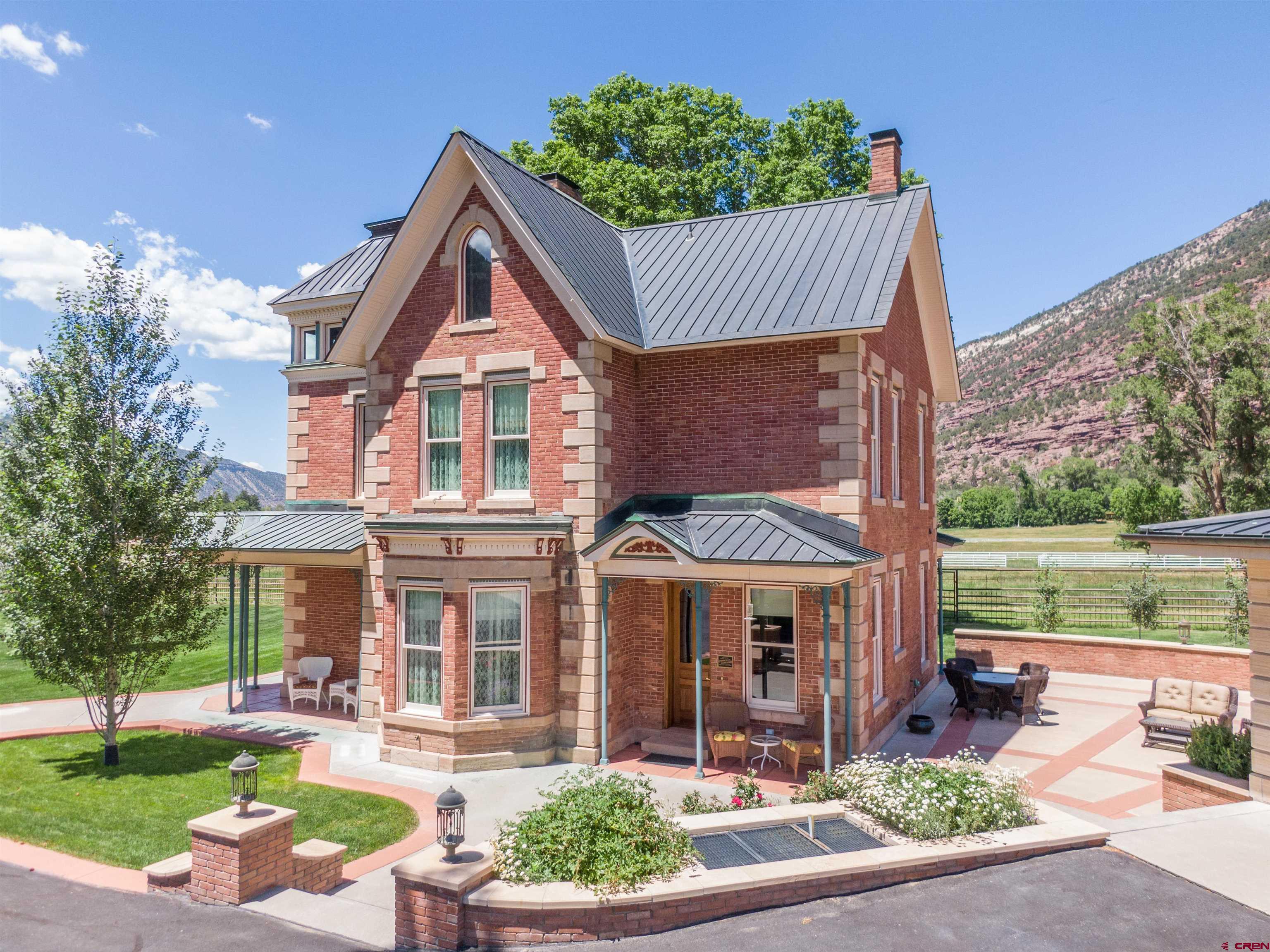 This Gorgeous Victorian Home is located in the beautiful valley just north of Ouray.  Surrounded by the majestic San Juan Mountains, this historic gem is listed on the National Historic Registry. Construction began in 1886 and was completed in 1888 by George Andrew Jackson, who is credited with discovering the first commercial gold deposits in Colorado and was the nephew of Kit Carson.  Locals affectionately refer to the house as "The Poor Farm" due to its history as a residence for indigent and sick miners from 1914 to 1937. It later became a private residence in the 1950s. In 2000, a local judge and builder purchased the home and began an incredible 10-year restoration project. Updates included all-new plumbing and electrical systems, foam-insulated interior walls, a copper roof, new subfloors, central heating and cooling, and new doors and windows.  The next owners, who purchased the home in 2011, completed the restoration by 2013. The level of care and craftsmanship throughout is truly something you must see to appreciate. Custom walnut millwork, crafted by a local artisan, adds elegance to the interior doors, windows, baseboards, and cabinetry. Much of the original gingerbread detailing still graces the exterior, along with original elements of the staircase that leads from the foyer to the second level. Marble and wood floors are featured throughout the home.  The kitchen features reproduction Heartland appliances—including two ovens, a broiler, warming drawer, refrigerator, and dishwasher—creating a charming vintage ambiance with modern functionality. The finished third-story attic offers an office space and two bonus rooms.  There are three beautifully restored bedrooms, including an elegant primary suite, and three full bathrooms. The lawn irrigation system is fed by a 100-gallons-per-minute water well. Priority water rights on the Hosner Brownyard Ditch feed the pond and over an acre of agricultural land. The house itself is supplied by Tri-County Water.  The three-car garage includes in-floor heating, a fourth full bathroom, and a parking pad with a 30-amp plug for your RV. The private, expansive patio features an outdoor kitchen—perfect for entertaining.  This one-of-a-kind Victorian home will be sold fully furnished, with many extras included.  Call today for a showing!