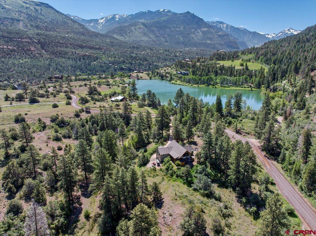 This beautifully remodeled mountain retreat offers the perfect blend of luxury, adventure, and water access, located on a private 1-acre parcel between Ridgway and Ouray in the exclusive Black Lake community—just a short drive from Telluride. With nearly 100 acres of shared open space including a private lake, parks, trails, and direct access to public lands, this property is a dream for outdoor lovers who crave year-round recreation like hiking, biking, fishing, kayaking, and paddleboarding. Set just off scenic County Road 17—a favorite route for cyclists and hikers—the home is accessed through a gated entrance and a stained concrete drive that leads to a knoll-top setting with stunning 360-degree views of the surrounding mountains and valley. Inside, the home is thoughtfully designed for comfort and connection, featuring soaring cathedral ceilings, rustic log accents, a dramatic floor-to-ceiling stone fireplace, and a gourmet kitchen with custom cabinetry, granite countertops, and high-end appliances. Two main-level suites include spa-style bathrooms and private outdoor access, with one offering a vaulted glassed-in sitting room and wet bar—ideal as a master or luxury guest space. The lower level includes two additional bedrooms, a full bath, laundry, and a walk-out to the oversized two-car garage, while the spacious loft provides a flexible area for an office, playroom, or media space with access to a covered deck overlooking the forest and peaks. Four separate outdoor living areas allow you to enjoy the changing seasons in comfort and privacy. Ownership includes full access to the Black Lake estate and its extensive conservation easement, which keeps property taxes low and ensures protected beauty for generations. With modest annual dues covering professional maintenance of the lake and grounds, you’ll enjoy peace of mind along with unmatched natural amenities. Whether you’re skiing in Telluride, soaking in the Ouray Hot Springs, biking Ridgway’s scenic roads, or simply relaxing on your deck by the lake, this exceptional home places you in the heart of Colorado’s most iconic mountain lifestyle.