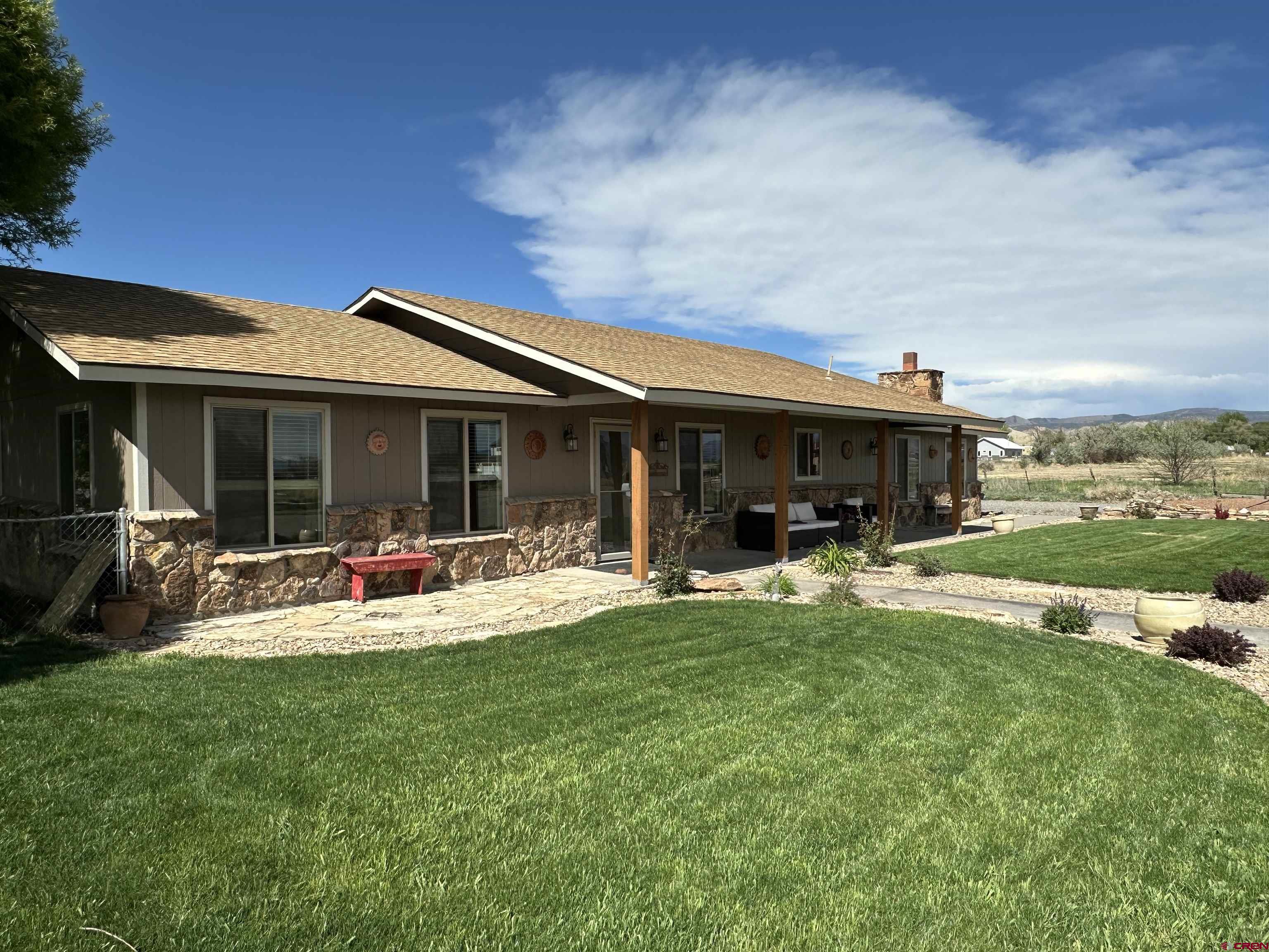If you are looking for privacy and a country feel, but you want to be close to town, this is the perfect property for you! This beautiful 2250 square foot ranch style home on 19.62 acres has it all. The home features an open floor plan with two dining areas, a large kitchen with granite countertops, tons of storage and much more. The heating is forced air natural gas, and the cooling is central air. There are laminate and tile floors throughout the house. The house is all one level, so it's ideal for people with mobility concerns. The is a cozy private den in the primary bedroom with a wood burning fireplace.  There is approximately 17 acres planted in grass hay. The crop averages 850-900 small bales each cutting two times a season. There is a shed barn and pasture for horses, there's a nice arena and round pen too. Electricity and domestic water are supplied to the barn.  This property has two full RV hookups. There are two storage sheds for your tools and toys. The yard is beautifully landscaped with a sprinkler system and drips. The back yard is fenced for your fur babies, with big shade trees and a huge patio. The front porch faces the gorgeous San Juan Mountains to the south. To the east, you can see the Black Canyon, to the north, the Grand Mesa is visible. There is a large gravel parking area in the front for your vehicles and equipment. There are no covenants, so running a business is fine. The north boundary of the property runs along the Lotzenhiser Canal. It's a lovely place to stroll and walk the dogs. Wildlife travel along the canal too. You can spot deer, foxes, many birds and some other animals. With the shares of irrigation water, you can grow the hay for your livestock, or you could plant another crop, such as row crops, trees, or a vineyard. The possibilities are endless! This property is very close to the Montrose Events Center Arena for winter riding indoors. It's also less than 2 miles from BLM and public lands for miles and miles of trails. Bring your mountain bike, dirt bike, ATV or just your horse and explore the beautiful Gunnison Gorge area. The Black Canyon of the Gunnison National Park is 20 miles away for some spectacular scenery, gold medal fishing, and great recreation. The property is 10 minutes from downtown, shopping, the hospital and great dining too.