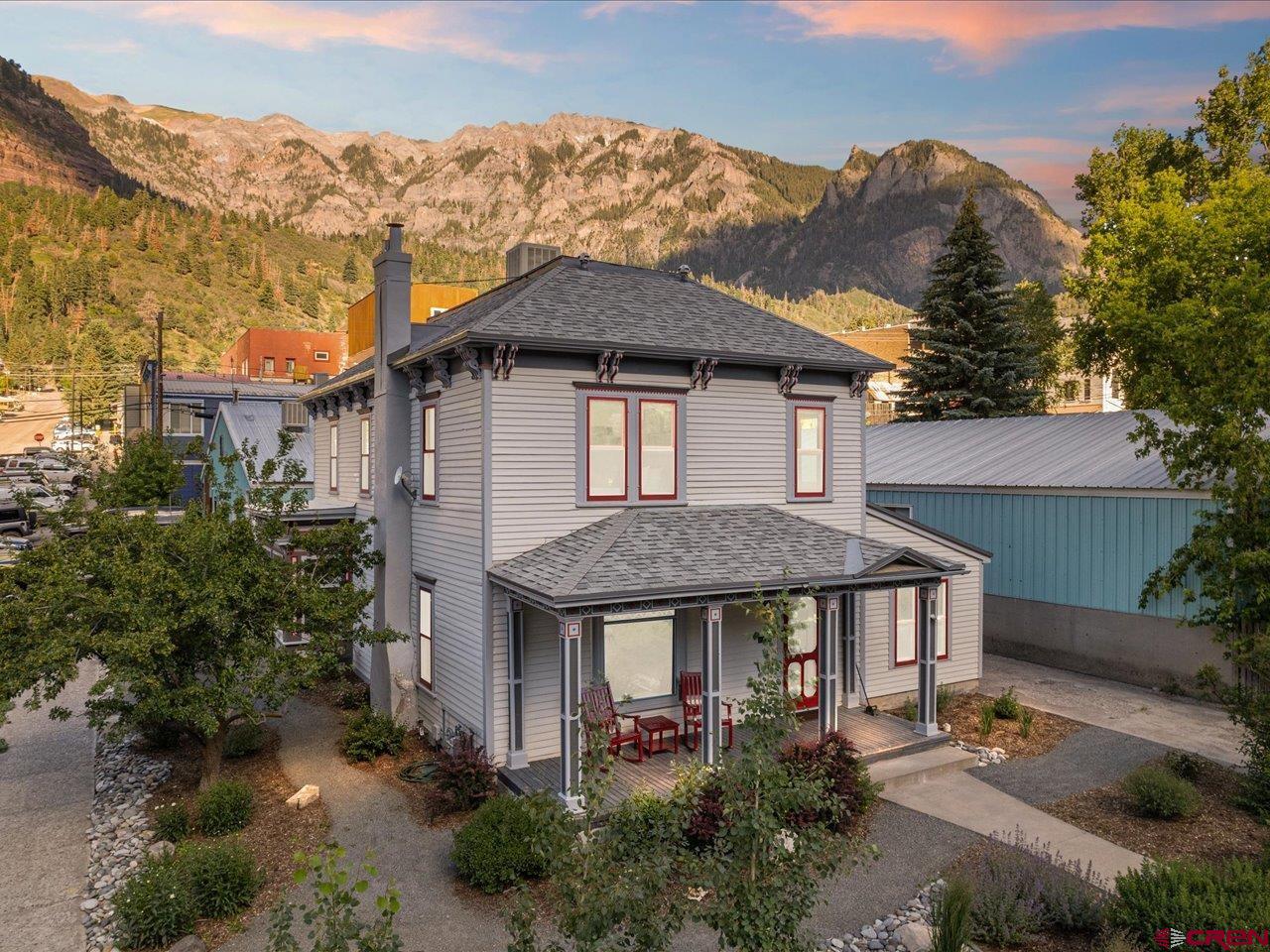 This fully remodeled 120-year-old gem seamlessly blends historic character with modern elegance, all in one of Ouray’s most sought-after locations. Ideally situated just across from the iconic Western Hotel and within easy walking distance to the town’s charming shops, restaurants, and hot springs, this exceptional property offers the best of both past and present.  Step inside to discover original architectural details lovingly preserved—solid wood doors, intricate trim work, vintage fixtures, and gorgeous hardwood floors—enhanced by tasteful, high-end updates throughout. The gourmet kitchen is a chef’s dream, featuring custom cabinetry, granite countertops, and top-of-the-line stainless steel appliances, opening into spacious living areas perfect for entertaining or relaxing in style.  With five generous bedrooms and 3.5 thoughtfully appointed bathrooms, the home is designed for comfort and flexibility. The main-floor en-suite includes a fully ADA-compliant bath, offering accessible luxury, while the upstairs primary suite provides a peaceful retreat with its private outdoor deck and spa-like bathroom, complete with a classic clawfoot soaking tub.  Step outside to a beautifully landscaped yard featuring a welcoming patio and cozy fire pit—ideal for gathering under the Colorado sky.  In addition to its residential charm, this property is a proven income-generating powerhouse. Zoned for commercial use, it has operated as a highly successful luxury vacation rental, consistently earning top ratings and praise. Ranked in the top 1% of all homes on Airbnb, it has been celebrated by guests as one of the platform’s “most loved homes”—a testament to its unique character, impeccable design, and unforgettable guest experience.  Offered fully furnished and meticulously decorated, this turn-key property is ready for its next chapter—whether as a cherished private home, a lucrative vacation rental, or both.  Don’t miss this rare opportunity to own a piece of Ouray’s rich history—elegantly reimagined for modern living and exceptional hospitality.