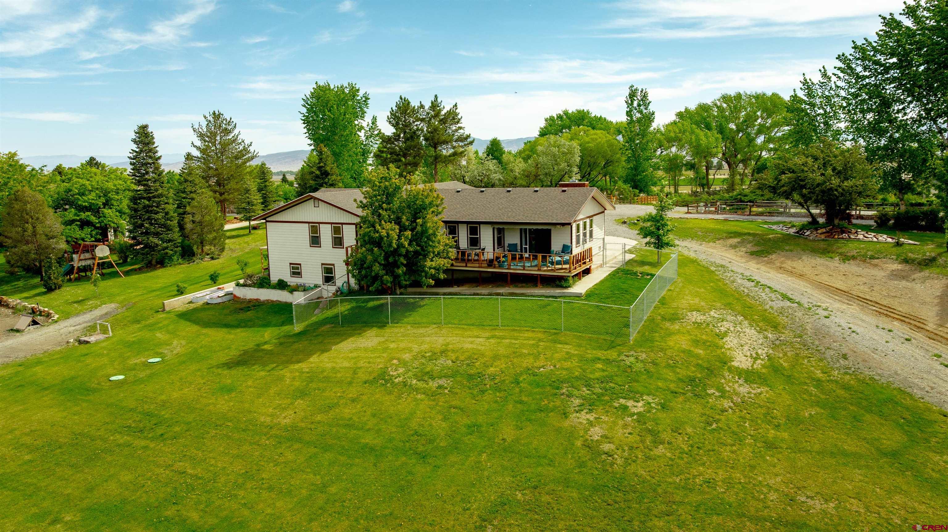 Beautifully Remodeled Ranch on 2.5 Irrigated Acres with Mountain Views. This move-in ready 4-bedroom, 3-bath Ranch-style home offers the perfect blend of modern updates and country living. Set on 2.5 irrigated acres in a desirable neighborhood, the property includes a 2-car garage and is thoughtfully designed with an open-concept layout and wide doors and hallways. Interior upgrades include wide plank laminate flooring, a gas insert fireplace, updated tile in all bathrooms, and plush carpet in each bedroom. Fresh paint throughout the home enhances the bright, clean atmosphere. The spacious main-floor Primary Suite features a large walk-in closet, en-suite bath, and sliding glass door leading to the deck—perfect for enjoying stunning views of the San Juan and Uncompahgre mountain ranges. The updated kitchen is equipped with stainless steel appliances, including a double oven and gas cooktop, durable Corian countertops, an island, and two pantries for ample storage. Downstairs, the finished basement includes a family room with walkout access to a concrete patio and hot tub, an additional bedroom and bathroom, plus another bonus room currently used as a bedroom (non-conforming).  Additional highlights include a large laundry room, pecan-stained trim and doors throughout, a radon mitigation system, fiber optic internet. Exterior updates include fresh paint, a brand new roof and raised garden boxes. With plenty of space for horses or hobby farm animals and room to build a shop, this property offers flexibility and room to grow. Don’t miss this rare opportunity—schedule your private showing today!