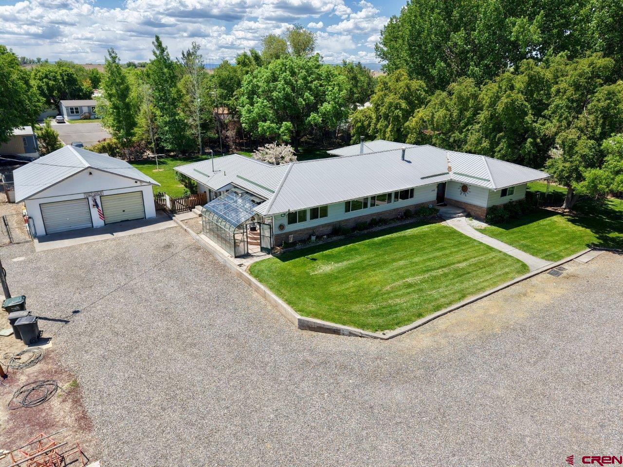 What wonderful property and home located in the country!  This sprawling ranch home with a basement has so much to offer, totaling 3320 square feet and located on 1.2 acres.  As you enter the circular driveway onto the property you cannot help but notice the mature and extensive landscape featuring blue spruce, aspen, fruit trees, along with many other trees, flowers and shrubs.  The irrigation water is supplied by a permitted well located on the property and distributed by the underground sprinkler system.  The avid gardener will love the solarium attached to the home. This property checks all the boxes for an owner needing ample storage with a 36 x 26 detached garage (that includes an office), carport, several storage sheds, plus additional outdoor parking locations.  Spend time in the summer relaxing on the large, covered patio.  Step inside this beautiful home that features oak hardwood floors throughout most of the main level, a gourmet kitchen with nearly new appliances, separate dining room, office, large laundry room with wash sink and freezer, wood stove, and the living/hobby/rec room in the basement has endless possibilities. This home does not have covenants, so there are many possibilities to how the   new owner can use this property without those pesky HOA restrictions.  Historically, this property has been used by owners with home-based businesses, so it could have the ability to serve this purpose for the new owner as well. Come take a look!