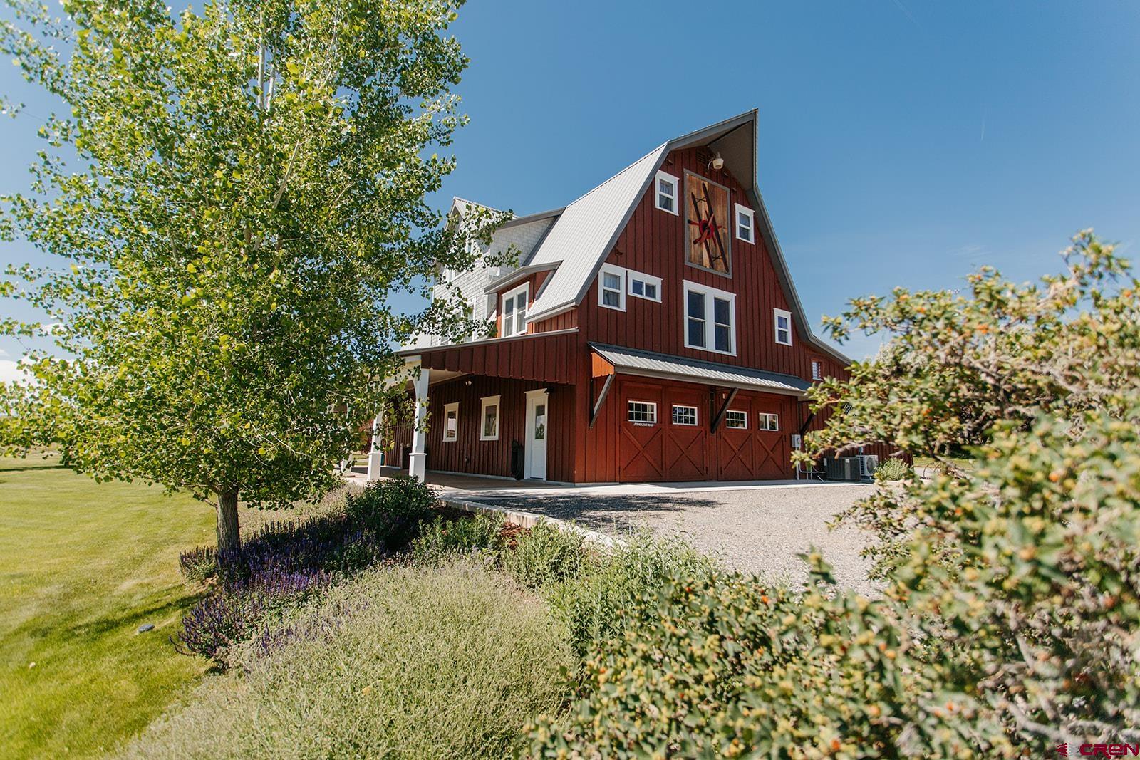 Welcome to one of Montrose’s most distinctive properties—an architecturally striking barn-style home nestled on over 3 acres of irrigated land with no HOA. With panoramic views of Colorado’s Western Slope and an exceptional layout spanning three thoughtfully designed levels, this home offers the perfect blend of character, comfort, and functionality, topped off by being meticulously maintained inside and out. Step inside the lower level, where a spacious heated and cooled shop opens to the oversized 4-car garage, welcoming foyer and handy updated ½ bath.  Upstairs, the second floor boasts a sun-drenched great room with a beautiful newly remodeled kitchen, large dining area with sweeping views and a walk-in pantry. The private primary suite on this same level features a spacious walk-in closet with natural light, and a bright and airy bath with step-in shower and Victorian tub. On the top floor, two generously sized bedrooms are connected by a charming sitting area, ideal for a playroom or quiet retreat, a full bathroom, laundry room, and extra storage room. Outside, enjoy manicured landscaping with a sprinkler system, mature trees, and pastures ideal for animals or hobby farming. Fruit trees, raised beds, a garden shed and wood shed —support a variety of agricultural or recreational uses. Whether you're seeking a lifestyle property, a mini-farm, or a private retreat just minutes west of town, this home delivers. With its iconic barn silhouette, expansive covered porch and patio, and gorgeous grounds, it's truly a one-of-a-kind offering in Montrose. Don’t miss your opportunity to make this unique and move-in-ready country estate your next home.