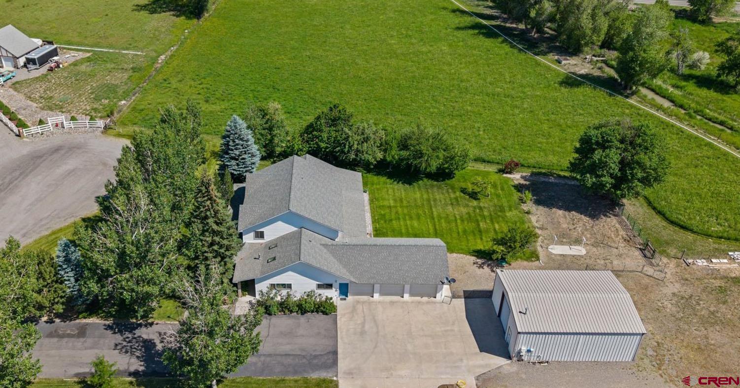 Spectacular Spring Creek Estate on 3+ Irrigated Acres with Spacious, Character-Filled Residence and Massive Shop! This is the idyllic property you've been waiting for, enabling you to live your best Western Colorado life. Tucked in at the end of a cul-de-sac, towering trees, lush, sprawling lawn and a stately, wraparound porch make the curb appeal on this home something out of a dream. Warmth, pride of ownership, and character shine throughout this versatile and spacious floor plan, which will accommodate whatever and whoever you're bringing with you. The gourmet kitchen includes everything the discerning chef and entertainer is looking for; a huge stainless and copper range top framed by brick, and a vaulted ceiling with skylights to elevate the atmosphere. The en-suite is on the main level of the home and has plenty of extra room for a reading nook, yoga mat or larger furniture. The en-suite bath has new flooring, a classy, clawfoot ceramic soaking tub, a tiled walk-in shower, and a walk-in closet with tons of storage. The living room is huge and provides easy access to the backyard, creating excellent indoor-outdoor living functionality. The main level of the home also features an office, which could function as a library, workout space or entertainment den. It also has a utility/laundry room which has extra room to keep the mess out of sight. Upstairs are 3 more guest bedrooms, with oversize closets and plenty of space for accommodating visiting loved ones, a craft or hobby room, or additional office/workout space. The 3-car garage is extra deep and would store most larger vehicles with ease, all the while not compromising on storage room. The main event of the home might be the shop, which comes with extra tall and pull-through doors to accommodate RV's, is heated and insulated, provides endless room for tinkering and projects, and is the ideal zone for toys, boats, hobby cars and whatever else your heart desires. All new Andersen windows in 2018, a new furnace last year powers the desirable in-floor heat system, and numerous updates throughout such as paint, lighting, fixtures, countertops, flooring and more make the value here a no-brainer. The potential for a hobby-farm or garden paradise is palpable and in every direction you look. Cherry and pear trees galore, a spacious field to accommodate 4-legged friends, gated pipe and flowing irrigation water, the world is your oyster in this magical environment teeming with life and potential. Secure Your Slice of the Ever-Elusive, Spring Creek Dream for Under $1m, Experience It For Yourself Today!