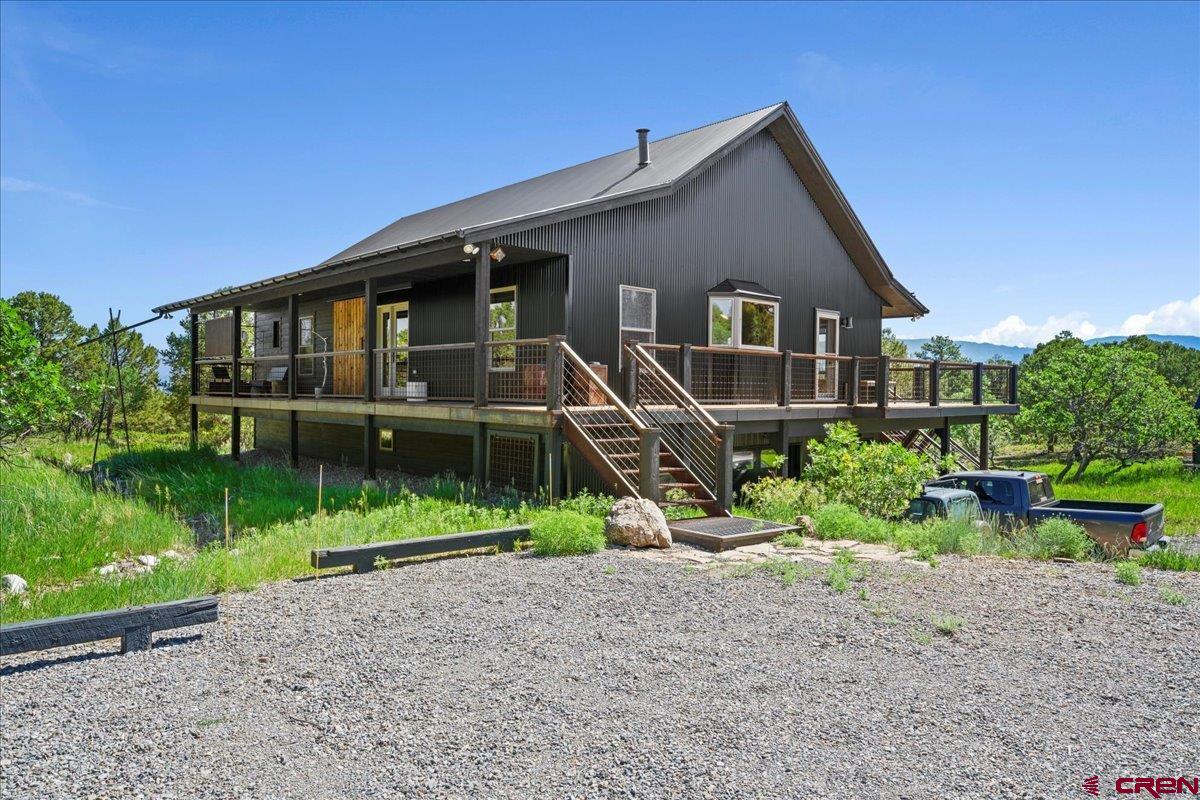 Experience the best of Colorado mountain living in this beautifully updated single-family residence, located above the charming town of Ridgway in desirable Loghill Village. Nestled on 5 private acres surrounded by towering Ponderosa, Piñon, and Juniper trees, this home offers the perfect combination of seclusion and breathtaking views. Enjoy panoramic vistas of the Cimarron Ridge in the San Juan Mountains on the expansive wrap-around deck. Inside, the home features modern mountain rustic finishes, creating a warm and inviting atmosphere. Thoughtful built-ins throughout the home provide abundant storage and help keep your spaces organized. The open-concept living area is ideal for entertaining. With three bedrooms and three baths, there’s plenty of room for family and guests, as well as a separate office, and a private studio offering peaceful retreats. A heated two-car attached garage adds convenience year-round, whether you’re heading out for adventure or returning home to watch the alpenglow light up the peaks.