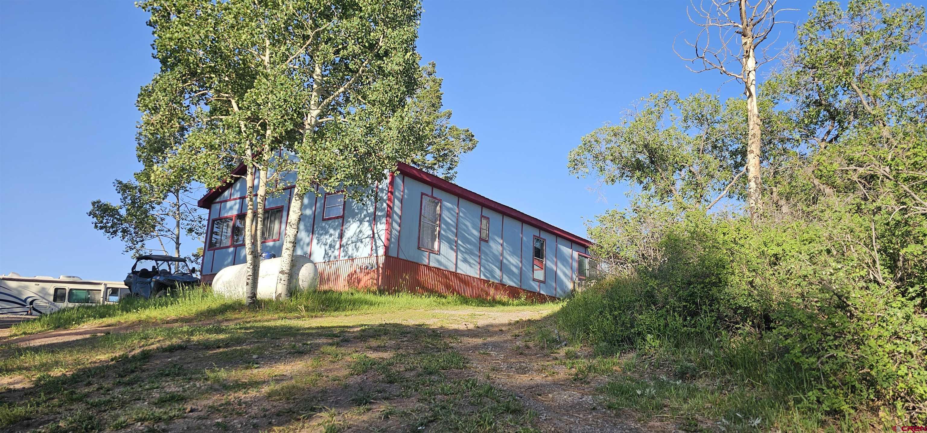 Escape to serenity in the mountains with this charming 4-bedroom, 3-bathroom manufactured home nestled on 1.21 acres amid majestic Aspen trees in the coveted Elk Meadows Estates community of Ridgway, CO. Spanning 2,025 square feet, this 1979-built residence offers an ideal canvas for those eager to customize and infuse with modern touches.  Step inside to discover a welcoming blend of laminate, carpet, and tile floors throughout. The open layout seamlessly integrates living, dining, and kitchen areas, while a dedicated room provides the perfect workshop, hobby space, or home office—supported by fiber-optic internet for seamless connectivity.  Outside, an oversized storage shed provides ample space for gear, tools, or seasonal supplies. Imagine sipping coffee or hosting gatherings on the spacious grounds shaded by Aspen groves, with peaceful views of the surrounding peaks.  Located under two miles from pristine National Forest access and just minutes from downtown Ridgway, this home places outdoor adventure right at your doorstep. Explore hiking trails or the San Juan Hut System, enjoy winter sports like skiing and snowmobiling, or simply immerse yourself in wildlife—elk, deer, turkey, and more are frequent visitors.  Elk Meadows Estates is a serene, incorporated mountain subdivision known for its natural spring water and tight-knit, nature-loving community. Plus, with strong demand for rentals in the area, this property doubles as an attractive long–term investment.  Opportunities like this, at such an accessible price, don’t come around often. Embrace the mountain lifestyle you’ve been dreaming of—schedule your private showing today!
