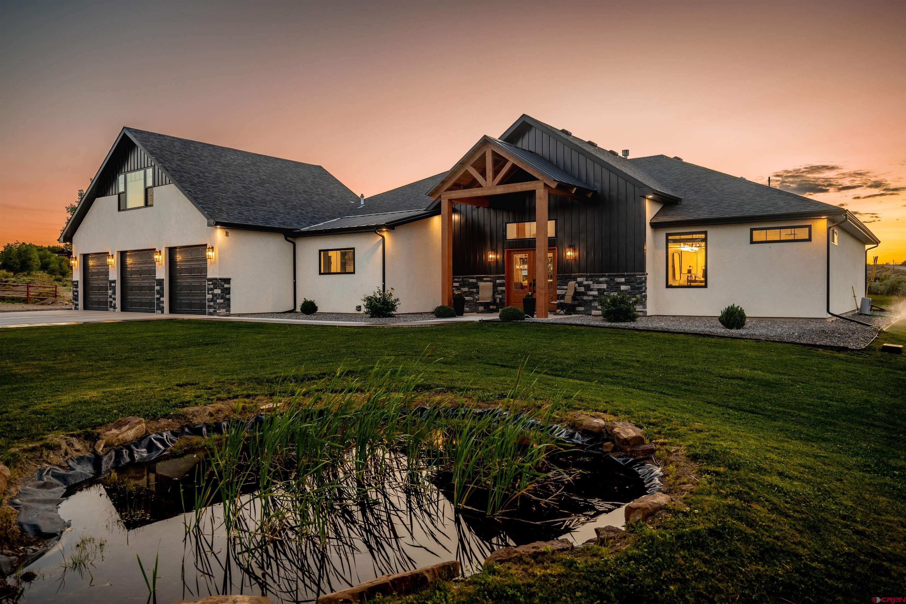 Modern Elegance Meets Colorado Charm on 3.05 Irrigated Acres  Modern and cozy unite in this absolutely stunning custom home, perfectly nestled on 3.05 irrigated acres in the desirable Ponds Edge subdivision of Montrose. The property offers a private pond, spacious fenced yard, large covered porch, and beautifully maintained landscaping—creating an unforgettable first impression.  The home’s exterior features a striking mix of neutral stucco, stone, metal, and wood accents for a one-of-a-kind look. Inside, the open and airy living space is filled with natural light and centers around a floor-to-ceiling stone fireplace with a wood mantel, while large windows frame views of the back patio and pond.  The chef’s kitchen boasts a massive island with a single-slab quartz countertop, abundant cabinets, generous counter space, and seating at both the island and adjacent dining area. A walk-in pantry, stylish half bath, and spacious laundry with built-in storage bench add convenience. The oversized, deep 3-car garage offers ample room for vehicles and gear.  The luxurious primary suite is a true retreat, featuring a spa-like bath with a freestanding soaking tub, five-head walk-in shower, dual vanities, and beautiful finishes. Two additional bedrooms share a large full bath with dual sinks and excellent storage. Upstairs, a flexible heated and cooled bonus room provides endless possibilities.  Enjoy incredible outdoor living with the expansive patio, private pond, beautiful views, and peaceful country setting. This home is truly one of a kind—schedule your showing today!