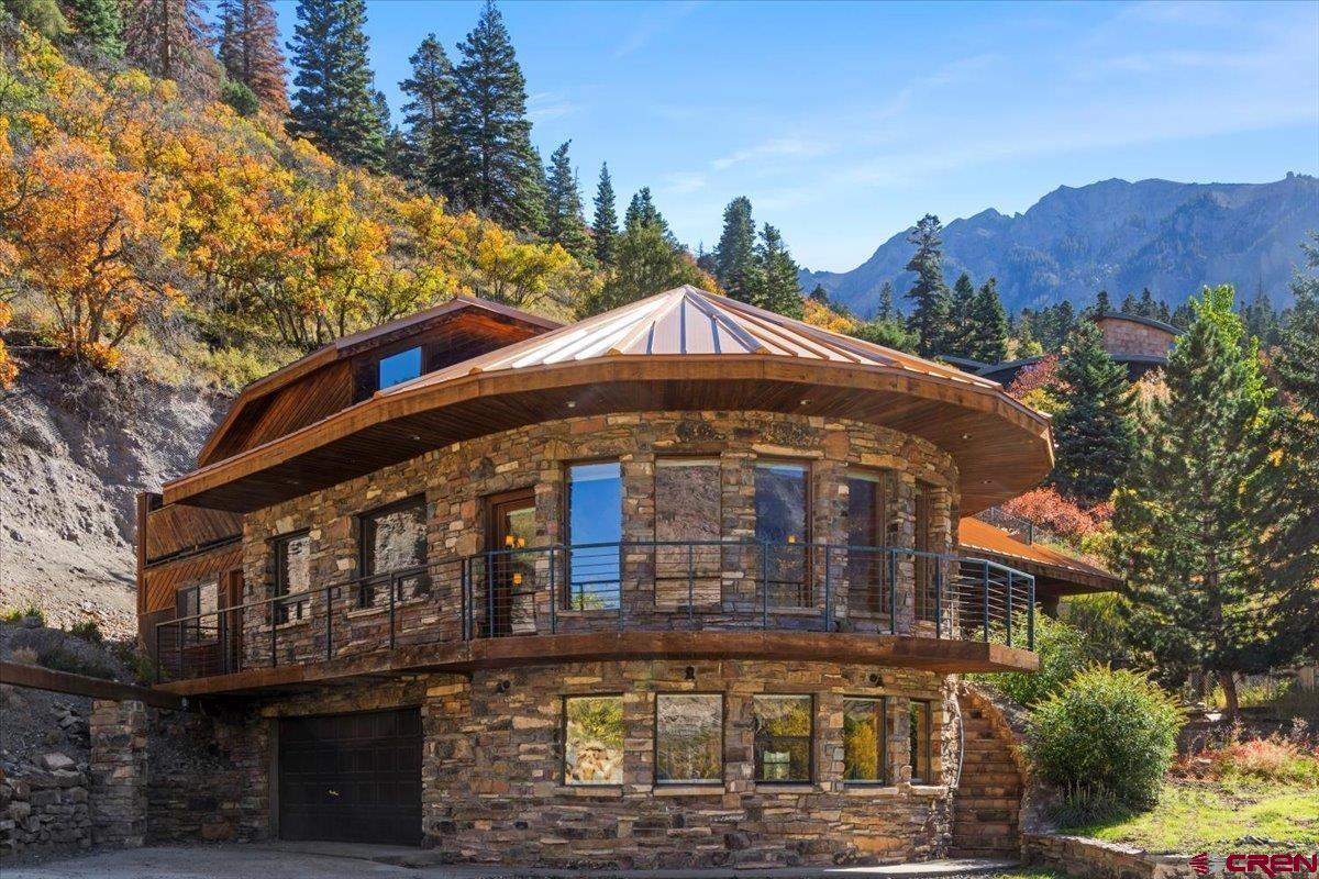 LOCATION IS PRIME FOR THIS beautiful home if you are looking for views.  This Iconic home sits at the top of the world looking toward mountains in all directions and sits with an overview of the City of Ouray from inside and outside of the home.  And yet, you are five minutes from downtown Ouray.  Easily reconizable from downtown Ouray with it's unique architechural style, just waiting for you to move in.  Surrounded by windows, the Living Room has beautiful Hickory floors carried out into the Dining Room and Kitchen.  Kitchen has built in breakfast nook, all stainless appliances including double ovens, dishwasher, 5 burner cooktop, microwave and a large walk-in pantry. There are 3 levels in this home.  The main floor where kitchen and living room are located also has a large office space with built in cabinets, just off of the laundry room with a 3/4 bath.  The Washer and Dryer are included.  Just around the corner you will find a 1/2 bath along with a large family room/den with a gas fireplace with granite and access to a small covered patio. One floor down  is the large and very private Master bedroom also surrounded by windows with views, and a large full bath with soaking tub and separate steam shower, double vanity and huge walk-in closet.  You can also access from this level  the garage/workshop.    One level up from the main level you will find an additional 4 bedrooms each with their own bathroom. There are patios and decks all around the home, including a hottub. There are two furnaces and the heat is gas forced air.   While some renovations are currently being finished you will see the  Newer roof on the home, new Marvin windows, new interior paint in some rooms, fixtures, etc.  This house is one to put on your list to see, there are very few homes like it in Ouray.   PLEASE NOTE:  Previously the home was being sold with two vacant lots.  Those lots are being subdivided from the home and sold seperately. Therefore, the price change is for the House only. Also some upgrades to the house are currently being made including interior paint, new carpet, new bathroom upstairs with glass shower door being installed and upgrade to patio and decking.  The lot with the house will be approximately 1 acre total  providing plenty of space for a new garage and large deck to be built  by the new owner.  Final Planning approval by the City of Ouray will be required prior to closing on the home.
