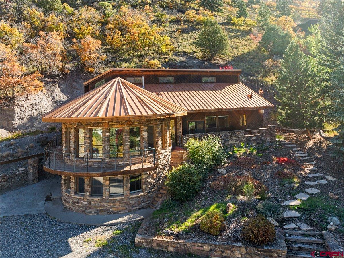 Luxury Mountain Retreat with Iconic Views – Ouray, Colorado  Location, location, location! Perched high above the charming resort town of Ouray, this one-of-a-kind luxury home offers breathtaking panoramic mountain views in every direction—while being just five minutes from downtown. With its distinctive architectural design, this iconic residence is easily recognizable from the valley below and perfectly blends sophistication, comfort, and natural beauty.  Inside, walls of windows showcase the surrounding peaks and fill the home with natural light. The inviting living room features beautiful hickory flooring that continues through the dining area and gourmet kitchen. The kitchen includes a built-in breakfast nook, stainless steel appliances—double ovens, 5-burner cooktop, dishwasher, and microwave—and a spacious walk-in pantry.  The main level also offers a large office with built-in cabinetry, conveniently located near the laundry room (washer and dryer included) and a ¾ bath. Just around the corner, you’ll find a welcoming family room or den with a gas fireplace framed in granite and access to a cozy covered patio.  The lower level is dedicated to a luxurious primary suite—a true retreat surrounded by windows and stunning views. The en-suite bath features a soaking tub, separate steam shower, double vanity, and an expansive walk-in closet. From this level, you can also access the garage and workshop area.  The upper level includes four additional bedrooms, each with its own private bath, offering plenty of space for family or guests. Multiple decks and patios surround the home, including one with a relaxing hot tub—perfect for enjoying the crisp mountain air and ever-changing scenery.  Recent updates include a newer roof, new Marvin windows, fresh interior paint in select rooms, updated fixtures, and more. The home is heated by two gas-forced-air furnaces for comfort year-round.  Note: This listing is for the home and just under one acre of land. Previously, two adjoining vacant lots were included in the sale—those parcels have since been subdivided and are now available separately. Buyers may consider purchasing the additional lots for expanded privacy or future development opportunities.  Truly a rare find in Ouray—homes of this caliber and setting seldom come to market..