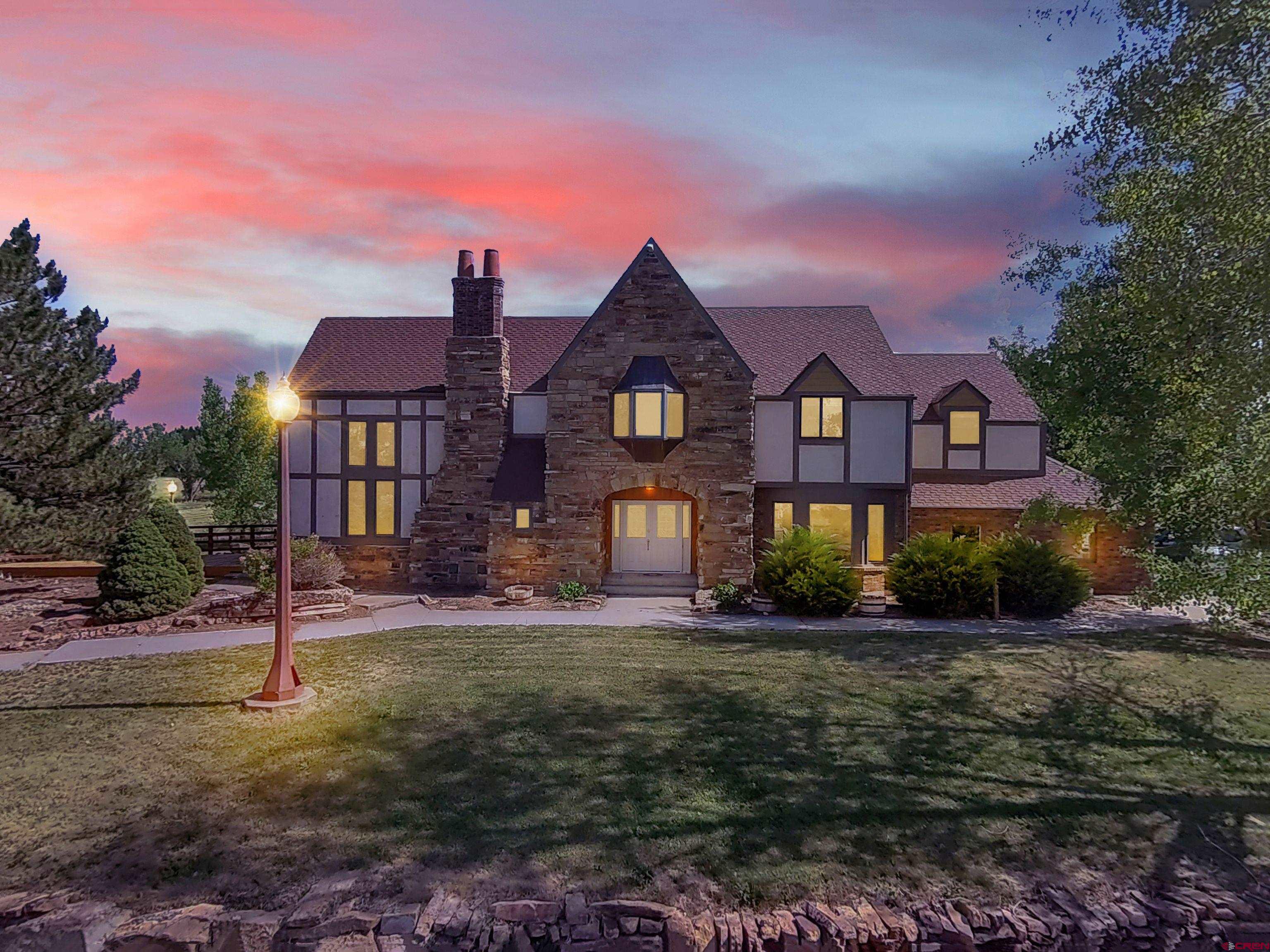 Expansive Tudor Estate on 5.44 Acres with Guest Quarters & Income Potential 7 Bed | 6 Bath | 4,651 SF | 5.44 Acres | Multiple Outbuildings | Separate Guest Quarters  Stunning 4,651 sq ft Tudor-style estate on 5.44 beautifully landscaped acres, perfect for multigenerational living, extended family, or home-based business. Main home features 4 bedrooms, a dramatic 16-ft ceiling in the great room, and a cozy TV room.  The finished basement includes a private 3 bed, 1 bath apartment with a separate entrance—ideal for guests or rental income. A detached studio unit with bath offers additional space for visitors, an art studio, or office.  Property includes multiple outbuildings: powered workshop, barn, open-sided shed, and lush gardens with a pond and waterfall. Fruit trees (apple, peach, plum) and garden space add to the charm.  Two Chipeta water taps (domestic + livestock) and 3.8 shares of Uncompahgre irrigation water. Decorative chimney cap adds unique historical flair—originally purchased by NFL legend John Elway.  A rare find offering space, privacy, and income potential in a peaceful setting close to town.