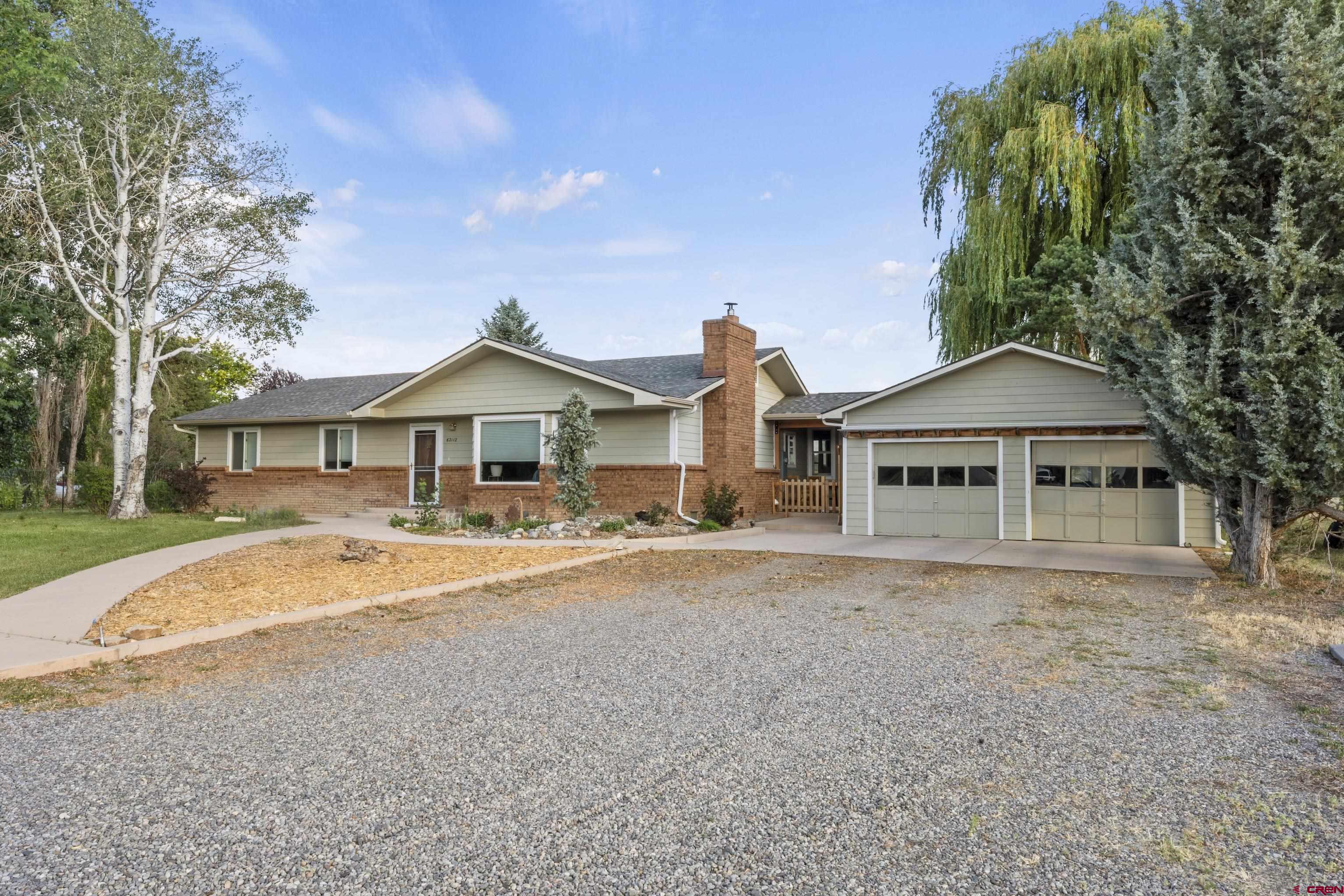 This beautifully maintained 2,195-square-foot ranch-style home, built on 2.28 acres, offers three bedrooms and two bathrooms, perfect for a family dreaming of a hobby farm. Renovated in 2017, the home boasts a modern kitchen with sleek appliances, a cozy den, and a luxurious master bathroom, blending comfort with style. Gorgeous oak hardwood floors flow throughout, complemented by a charming brick fireplace in the living room that adds warmth and character. Large windows flood the interior with natural light, creating a bright and inviting atmosphere. The master bathroom features a spacious walk-in shower with elegant tilework, a stylish vanity, and ample storage for convenience.  Outside, the property shines with thoughtful outdoor features. Elevated garden beds, enclosed by a tall deer fence, make gardening a breeze while protecting your crops from wildlife. The land includes a pasture area with irrigation water, ideal for sustaining lush greenery or supporting livestock. Mature shade trees, evergreens, aspens, and fruit trees dot the landscape, offering beauty and tranquility. A separate outbuilding provides versatile space—perfect for an art studio, workshop, pottery barn, kids’ playhouse, or extra storage. The newly rebuilt swamp cooler ensures the home stays cool during warm summers. With plenty of room for 4-H animals and family activities, this property is a haven for outdoor enthusiasts and those seeking a rural lifestyle. Come explore the endless possibilities this home offers!