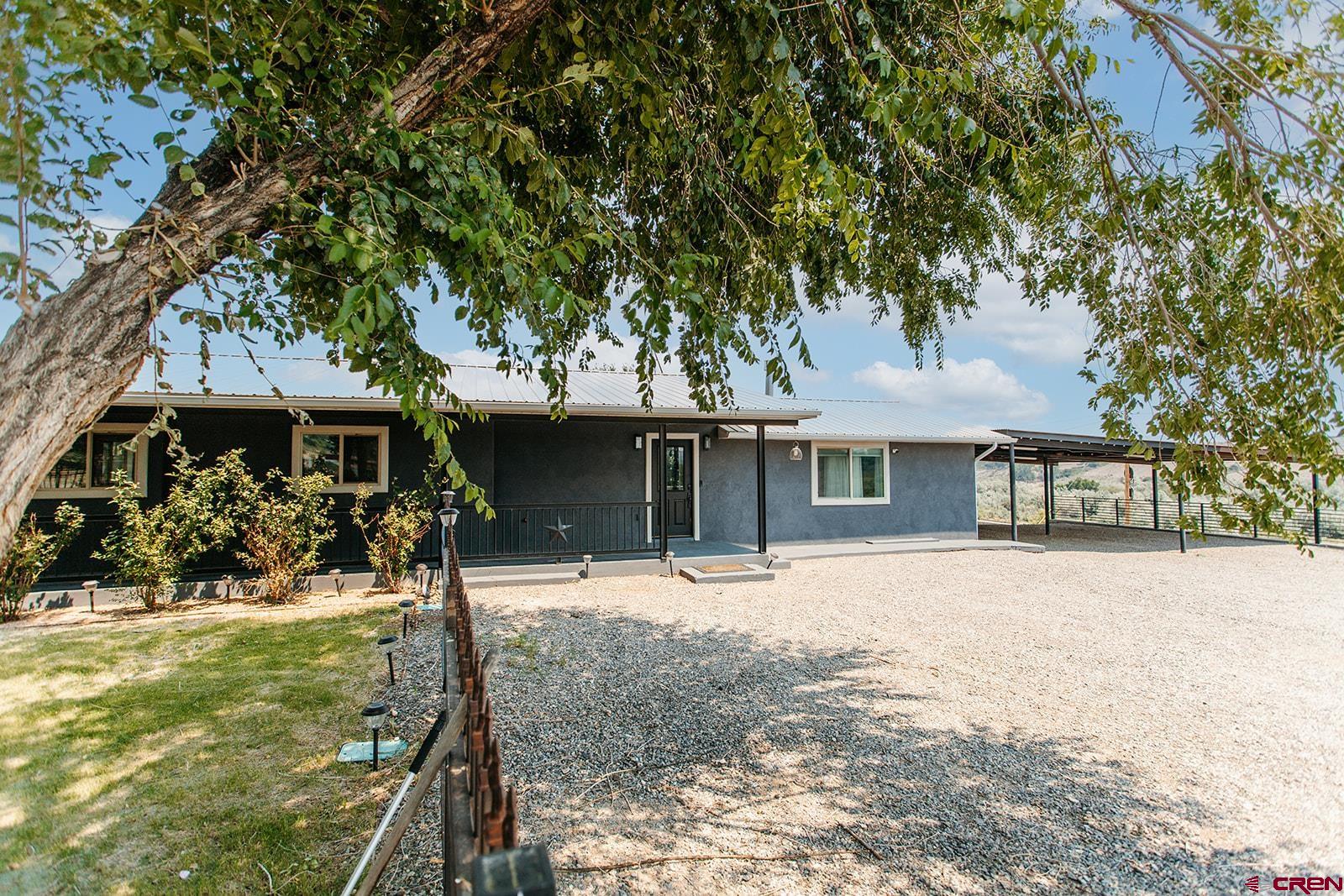 Welcome to this beautifully updated 3-bedroom, 2-bath home nestled on a private, fully fenced lot with expansive views and plenty of room for the whole family. From the moment you walk in, you’ll appreciate the warm, welcoming feel—featuring an open-concept living space with rich wood flooring, large picture windows, and a cozy fireplace perfect for family movie nights or game days. The thoughtfully designed kitchen is both functional and inviting, complete with stainless steel appliances, granite-look countertops, and crisp white cabinetry. Whether you're prepping weekday meals or hosting holiday dinners, this kitchen checks all the boxes. Retreat to the spacious primary suite or enjoy the generously sized guest rooms—perfect for kids, guests, or a home office. The updated bathrooms feature custom tile work, dual vanities, and a walk-in shower, offering both style and practicality for a busy household. A standout bonus space downstairs provides endless potential for a kids' playroom, media lounge, home gym, or teen hangout, complete with a rustic-style bar and industrial finishes. Step outside to enjoy the best of outdoor living with a fully fenced backyard, mature trees for shade, a covered patio for grilling, and wide-open space for pets and play. The large gravel driveway and covered carport offer ample parking for multiple vehicles, RVs, or trailers.This home combines comfort, character, and convenience—all in a peaceful setting with room to grow. Don’t miss this one-of-a-kind property that’s ready for your family to move in and make memories!