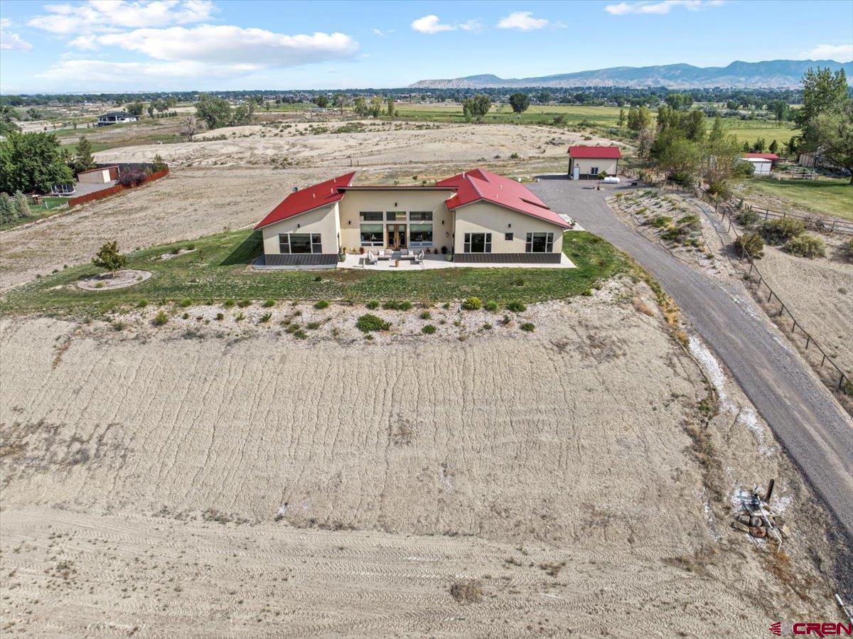 Built in 2018, this modern Mountain View home offers refined sophistication and thoughtful design across 3 bedrooms, 3 baths, a versatile flex room, and an oversized 3-car garage. Set on 4.84 irrigated acres with sweeping views of the San Juans, Grand Mesa, and Cimarron Ridge, the home showcases scratch-resistant laminate and tile flooring, quartz countertops, high-end KitchenAid appliances, and Delta fixtures. The great room features expansive Jeld Wen windows with automatic Hunter Douglas blinds in the great room and a propane gas-log fireplace. Enjoy comfort and utility with a large 4’ crawlspace, forced air system, and hot tub wiring in a private courtyard. The exterior includes a metal roof with gutters, a 500-gallon leased propane tank, a 26-zone Rainbird irrigation system (5HP pump with 3 shares of Uncompahgre Valley Water Users Association), and a beautifully built front pipe fence in 2023. Bonus features include a 24x24 shop with a tall overhead door, bright LED lighting, and a farmer’s faucet in the south field. The garage is wired for a welder, and conduit is in place for Elevate fiber internet. This is mountain living with style, space, and high-end infrastructure—ready for your lifestyle.