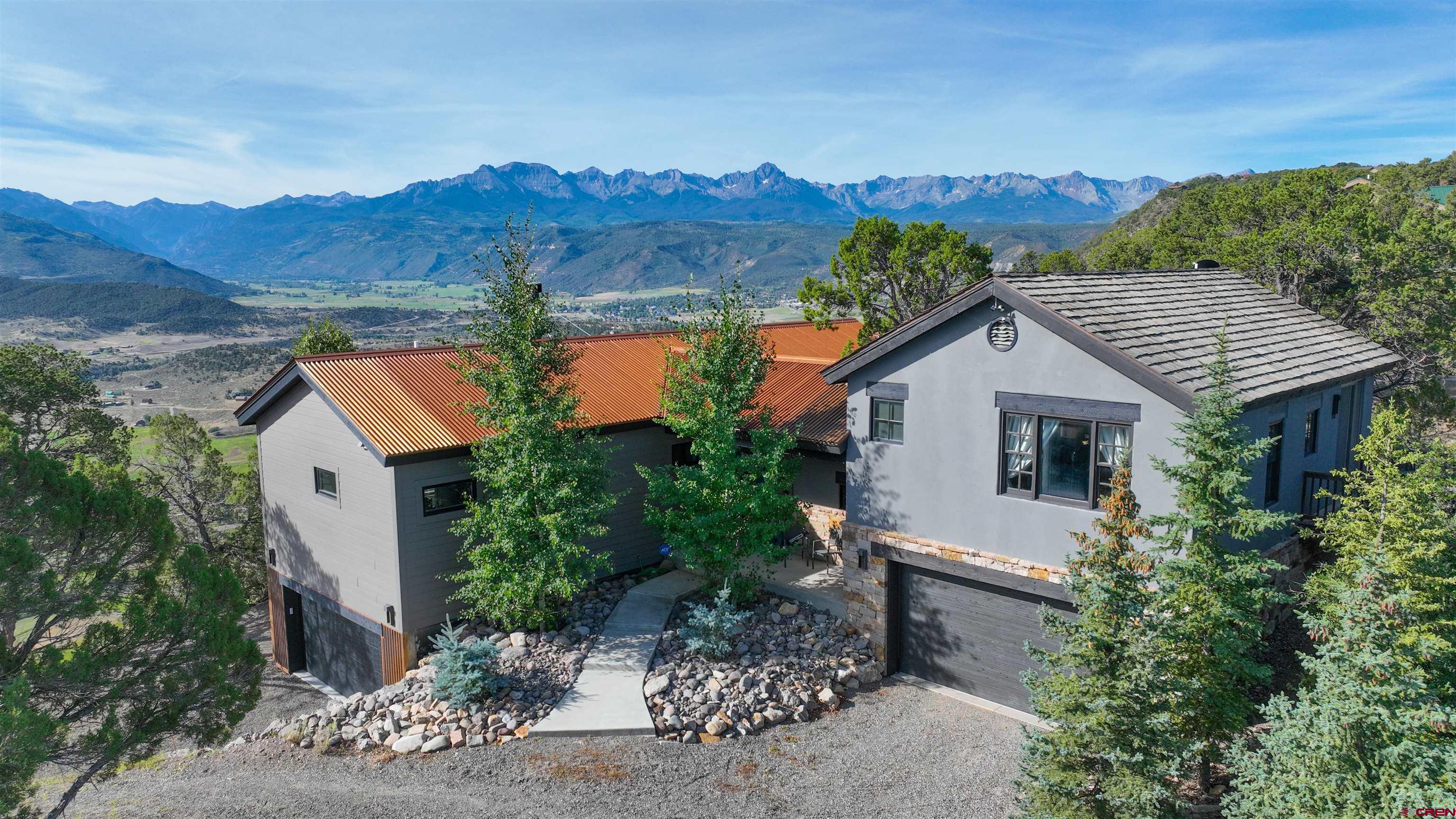 Mountain Luxury with Sweeping San Juan Views  Welcome to 150 Enclave Road. Set on 1.8 acres with breathtaking views of Mt. Sneffels, the San Juans, and the Cimarrons, this dual-residence property offers refined living in the heart of Colorado’s adventure country   Main Residence (1,992 sq ft | 2022 Build) Crafted for mountain living, this beautifully designed home features a wood-burning fireplace, vaulted ceilings, large windows, and seamless indoor-outdoor flow. Stainless appliances and including a wine fridge. Enjoy central heat & A/C, high-end finishes, and a massive wraparound deck with hot tub for soaking in the panoramic scenery.  Guest Cottage (1,005 sq ft |  Perfect for additional income avenues, guests or multi-gen living, this charming attached cottage features in-floor radiant heat, a gas fireplace, full kitchen, whirlpool tub, and dual porch mountain views. The walk-out level includes a heated 2-car garage, laundry/mechanical room, and bonus sleeping den.  With trail access to BLM and Ridgway Reservoir, you’re minutes from hiking, paddleboarding, and four-season adventure. Golf at Divide Ranch & Club, relax at Chipeta Spa, or ski Telluride all within an hour.  2,997 total heated sq ft | Designer finishes | Dual fireplaces | Exceptional privacy. A rare offering combining natural beauty, outdoor access, and peaceful luxury. Call for full details and the Furniture Inclusion Package being offered with the Home at $30,000.00.