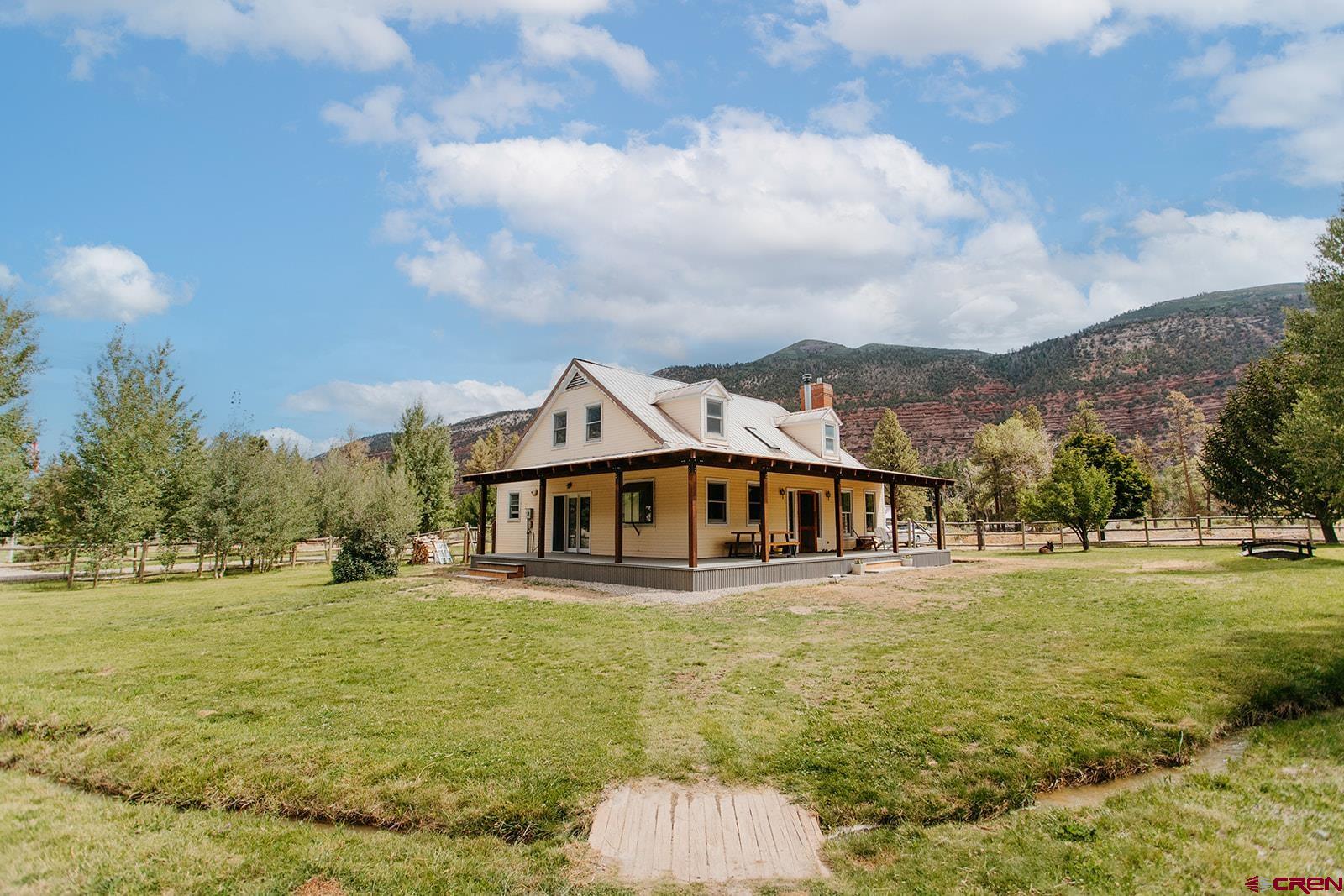 Welcome to your dream homestead retreat with unobstructed mountain views! Situated on a 4H-friendly, irrigated property, this versatile home combines rustic charm with modern upgrades—offering comfort, function, and room to grow.  Home Features: 3 Bedrooms / 2 Bathrooms, including a remodeled full bath and a primary suite with a wood stove and walk-in closet Expansive dormered upstairs bedroom with cubbies, built-ins, and a full upstairs bath Remodeled laundry/mud room for added convenience Engineered hardwood flooring, new carpet in the downstairs bedroom, and built-in shelving Vaulted tongue-in-groove ceiling and a second cozy wood stove Efficient on-demand hot water and hot water baseboard gas heating  Outdoor Features: Fenced and cross-fenced for animals—perfect for horses, chickens, and sheep Includes chicken coop, sheep pen, and horse setup with electric fencing Pond with irrigation water, charming meandering ditch through the property, plus a fire pit for year-round enjoyment Greenhouse  Brand new engineered exterior covered wrap around deck!  Irrigation via ditch and pump system: 2” pump pulls irrigation water (no flood irrigation) Pump also connected to sprinkler system  Extra perks: cherry tree, playhouse, and even a motorcycle track (can be leveled)