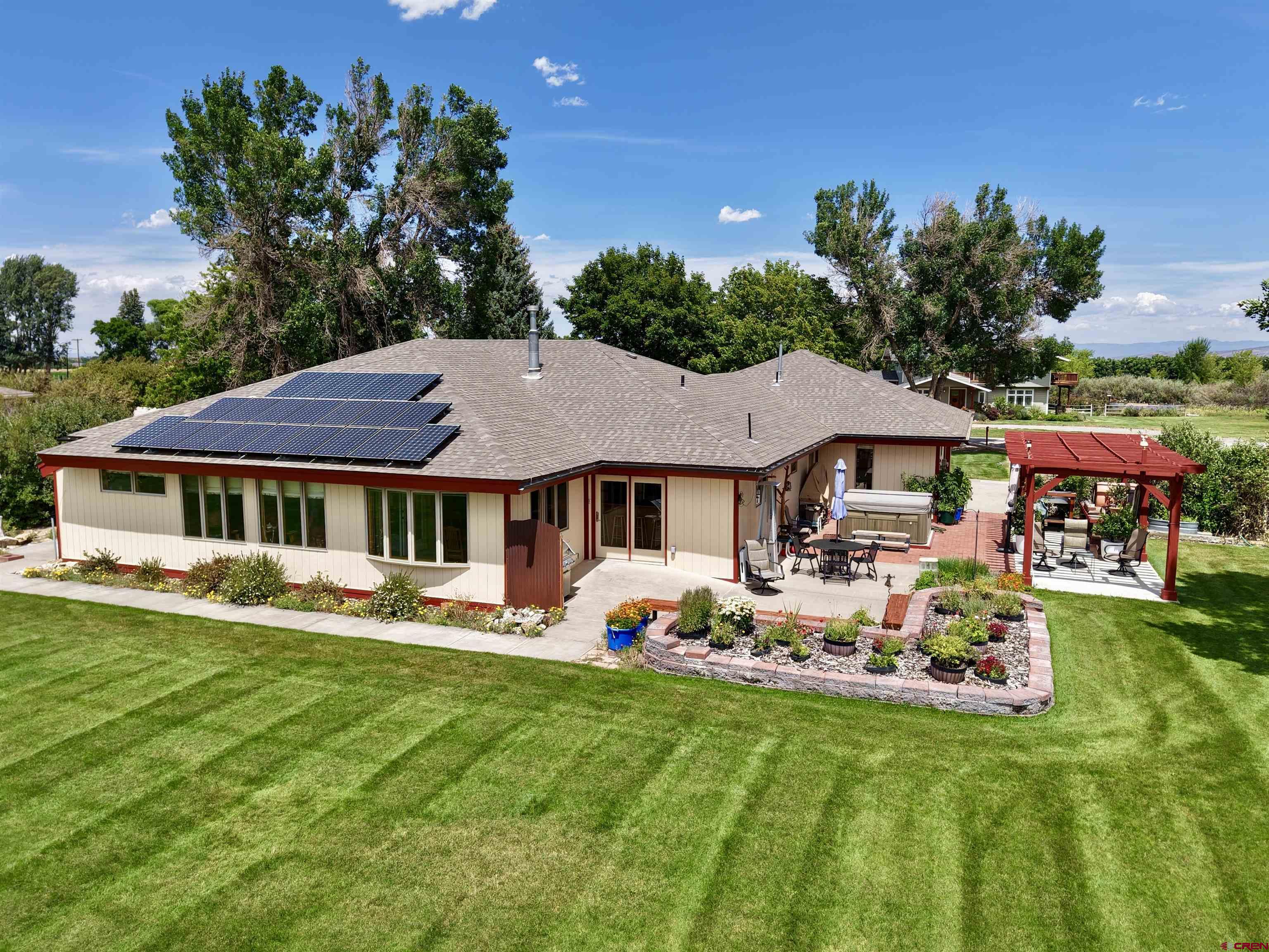 You don’t want to miss this opportunity to experience the perfect blend of comfort, style, and Colorado beauty in this custom-built single-owner home. This 2,944 sqft ranch-style home features unparalleled accessibility with zero steps and 36”+ wide doors throughout the entirety of the home. The solid 36” wide Douglas fir doors by Simpson were custom-ordered and carved and provide timeless style, durability, accessibility, and privacy. As you make your way up the entrance to the home, you’ll be relieved in the colder months as the front sidewalks on the north side of the home are in fact heated walkways! From the foyer, the home opens up with an inviting floor plan with an abundance of natural light from the south-facing wood-clad windows, and it’s truly ideal for both everyday living and entertaining. The entry, hallways, dining area, and kitchen are all covered in beautiful #1 Oak hardwood flooring. The living room is better stated as a great room with its vaulted ceiling adorned with beautiful structural beam work.  The kitchen is open with plenty of storage in the custom cabinetry and even two pantry closets. From the living room and dining room, you’ve got direct access to the large 12’x24’ tiled sun room facing south towards the beautiful San Juans. The sun room also provides access via double doors to one of the 2 primary suites in the home! The 4 bedrooms and 3 bedrooms in the home are laid out for flexibility and utility. Each side of the home has its own primary suite complete with dual shower heads and updated tile work. The other two bedrooms are very spacious and can be used as an office, study, craft room, guest room, workout room or any combination. The gas fireplace by Vermont Castings is centrally placed for ideal ambiance and cozy warmth. Step outside and take in the unobstructed mountain views that will leave you in awe every single day. Whether it’s sunrise over the peaks or a golden sunset, the scenery is nothing short of spectacular in this country setting just minutes from town. Extensive outdoor patio space on nearly all sides of the home. A large hot tub, custom outdoor wood-fired pizza oven, garden beds, pergola, etc.,the outside space is simply amazing! The irrigation water rights and automated sprinkler system provide everything you need to keep your landscaping lush and green all season long. There is a 12’x24’ lawn/storage building outside, and the attached garage is oversized at approximately 1,000 sqft and even has a gas unit heater so you can be comfortable with any hobbies or maintenance that may pop up. The home is extremely efficient with a solar system that is owned free and clear and geothermal heating and air conditioning installed by DMEA. The combination of open space, natural light, and panoramic vistas on this private dead-end county-maintained road makes this home truly one-of-a-kind. If you’ve been dreaming of a home where luxury meets nature, this Montrose gem is ready to welcome you. Call today to schedule a private showing and see the view for yourself!
