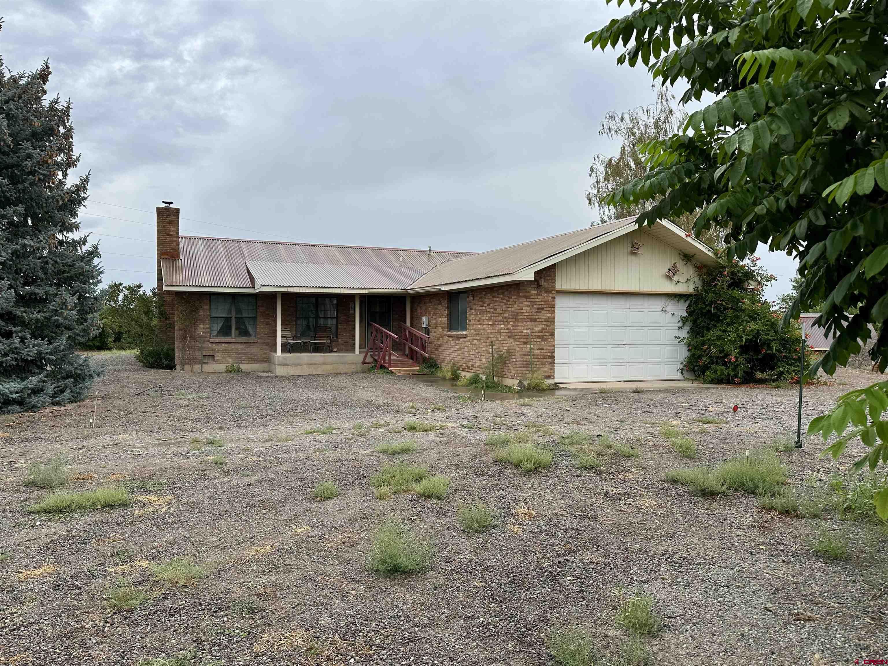 Nice quiet location for this brick home with 2 bed, 2 bath, 2 car attached garage, sitting on 26 irrigated acres.  This comfortable 1,440 sq ft home has an open kitchen living room with a wood fireplace and vaulted ceilings.  The primary bedroom has a 3/4 bath.  Also included is a 30-40 insulated shop with a one-bedroom apartment.  The land around the home is full of every kind of fruit tree that grows here and also two pecan trees.  The irrigated field is a good soil type capable of growing all local crops.  It is currently rented and is in Pinto beans.  Easy to maintain home with brick exterior and rusty metal roof, great location just a few miles north of Montrose and a great shop