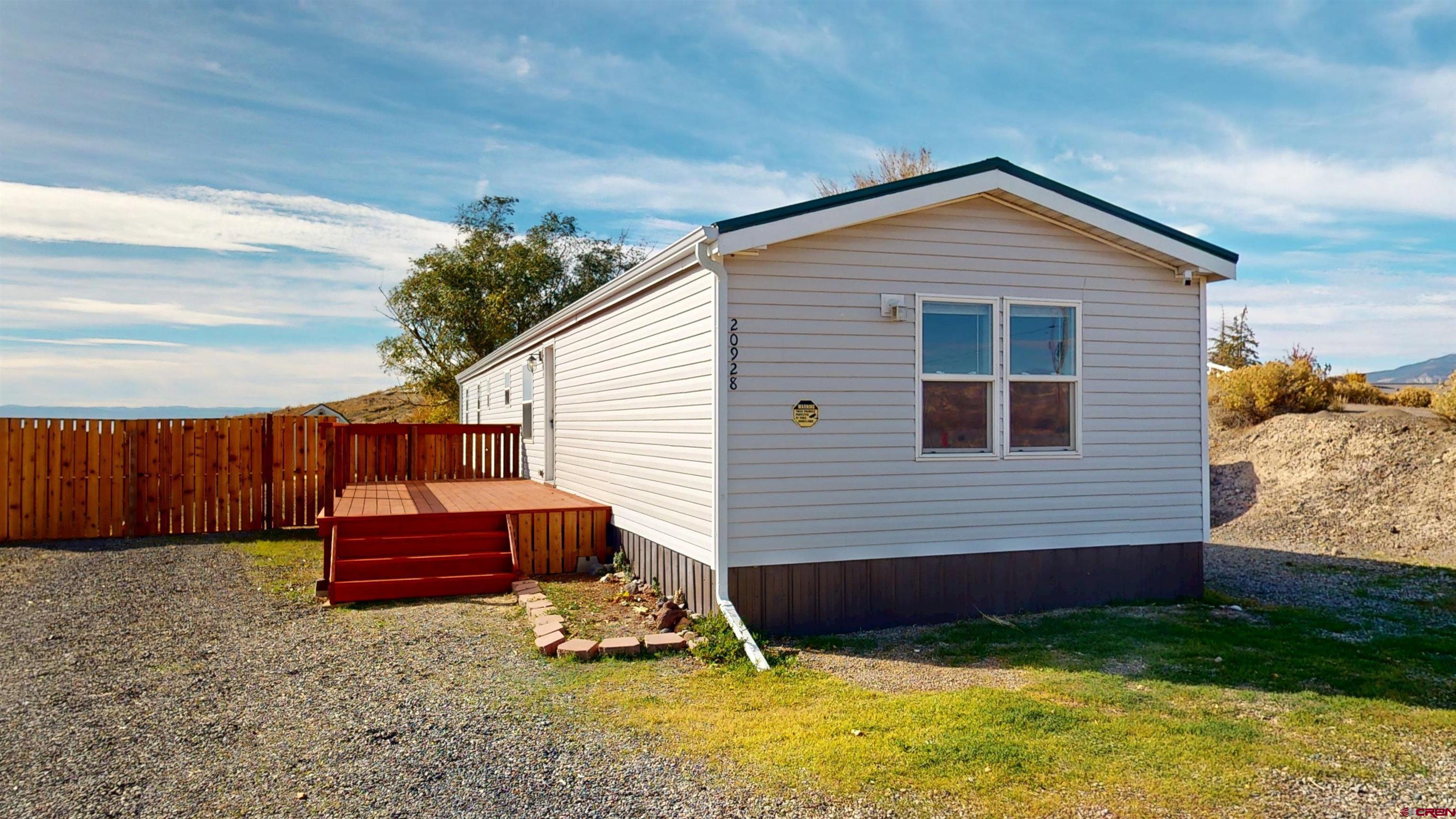 Check out these incredible views! This tidy 3-bedroom, 2-bath manufactured home, built in 1994, sits on 1.36 acres and truly feels like you’re on top of the world. Completely remodeled in 2021, the home features new drywall throughout, updated cabinets, modern bathrooms, and newer appliances. The inviting living area opens onto a spacious redwood front deck and a fenced yard that includes a storage shed—perfect for all your gardening tools. An attached garage/workspace offers a wood-burning stove and a single overhead door, while just outside, a sturdy double carport provides additional covered parking. Although much of the property is sloped, that’s the trade-off for the spectacular views that make this home so special.